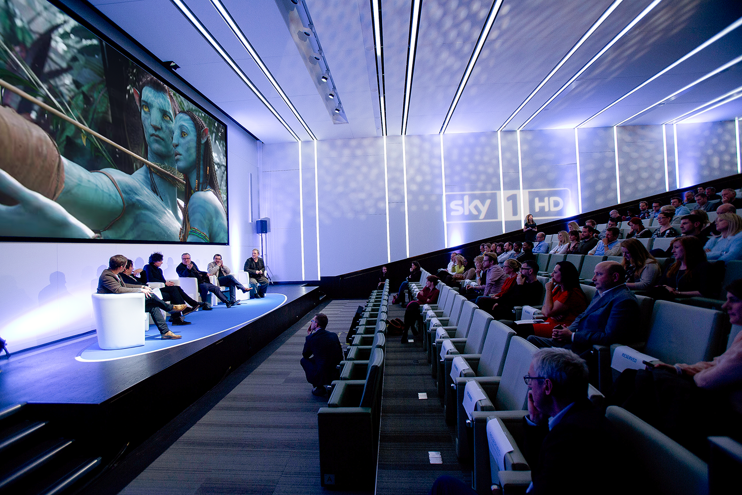 Auditorium panel discussion with tiered seating and engaging visuals at 30 Euston Square.