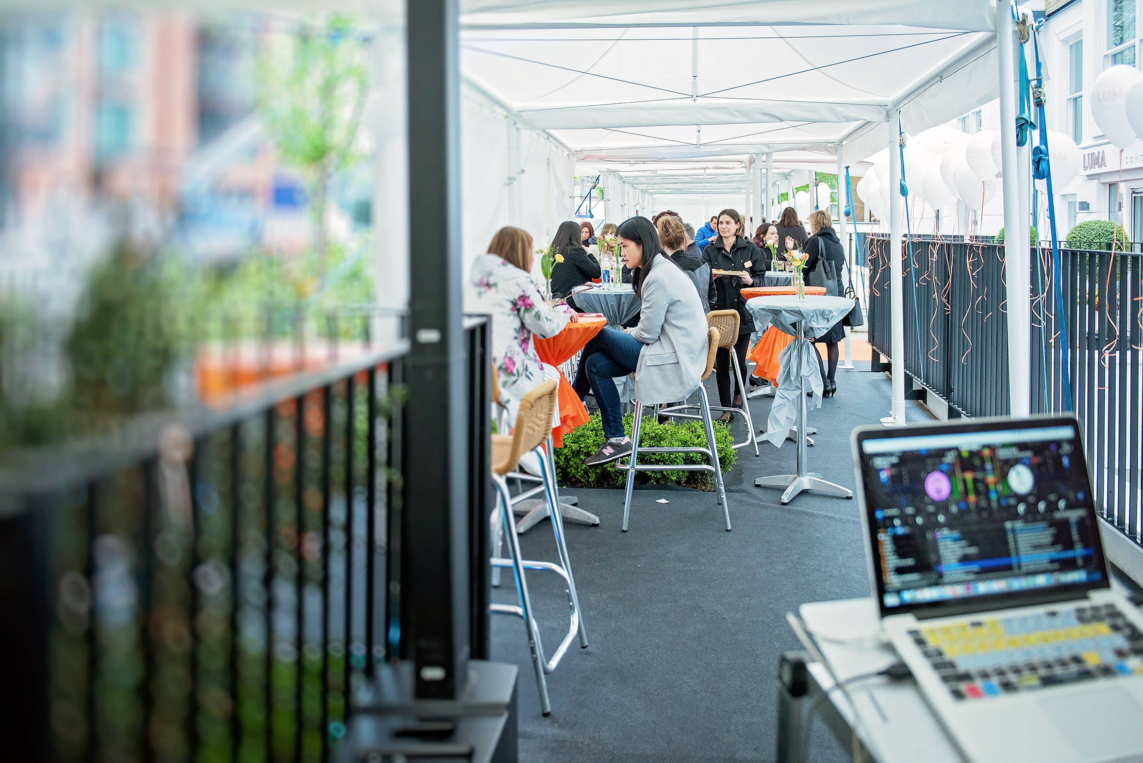 Vibrant outdoor event space at LUMA Concept Hotel with high-top tables for networking.