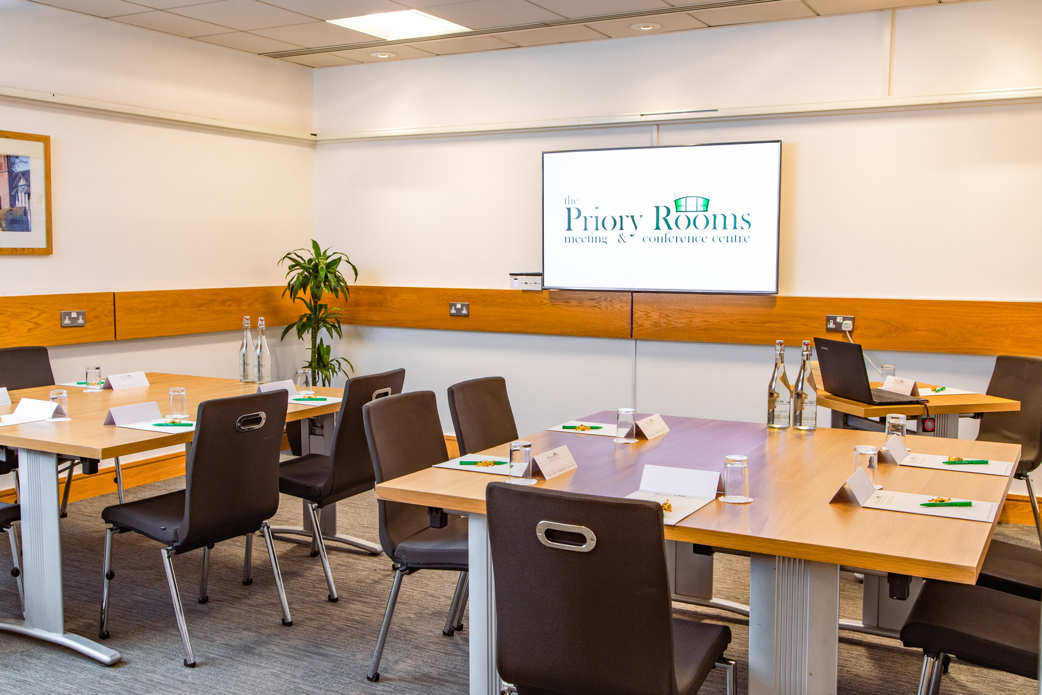 Margaret Fell in a professional meeting room with tables, notepads, and branding screen.