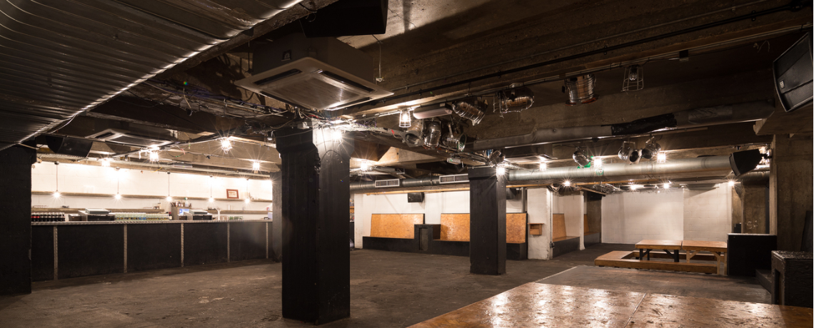 Versatile industrial event space with exposed beams, ideal for gatherings and parties.