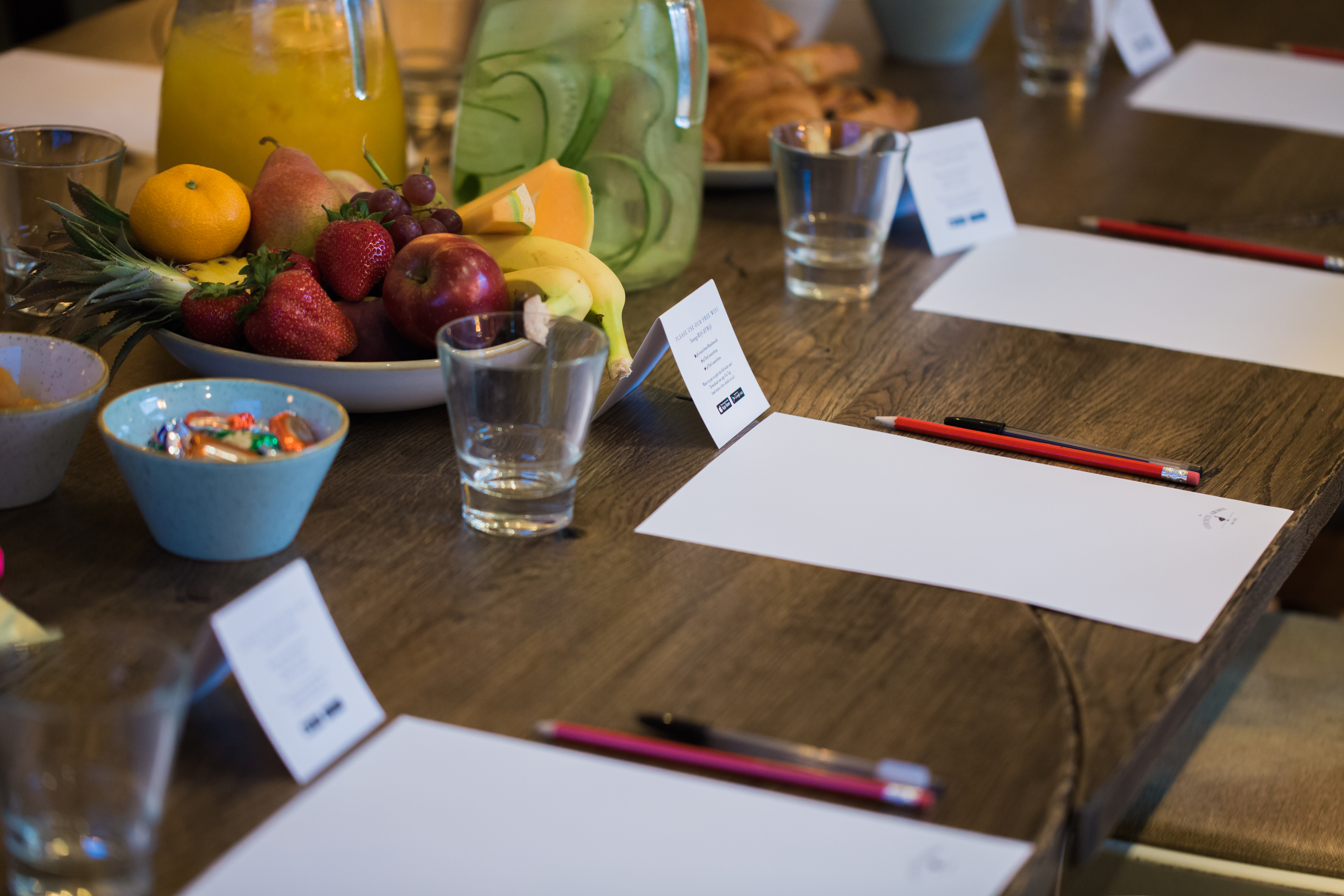 Meeting space with long table, notepads, and fresh fruits for creative collaboration.