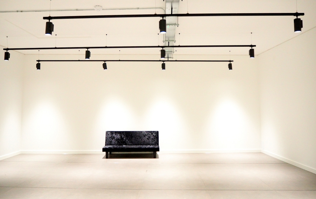 Minimalist event space with dark sofa and white walls, perfect for gatherings or presentations.