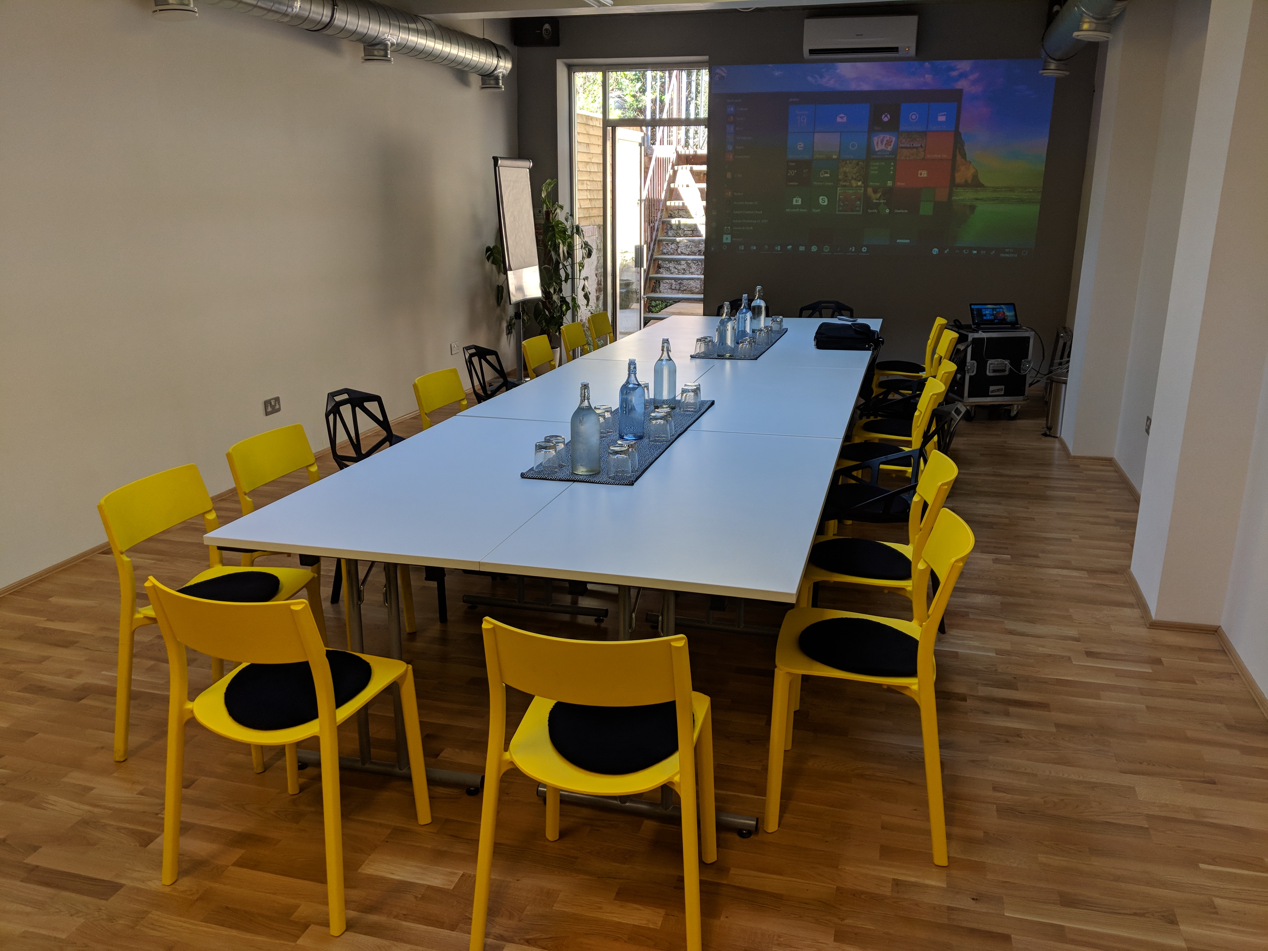 Modern conference room with white table and yellow chairs, perfect for workshops.