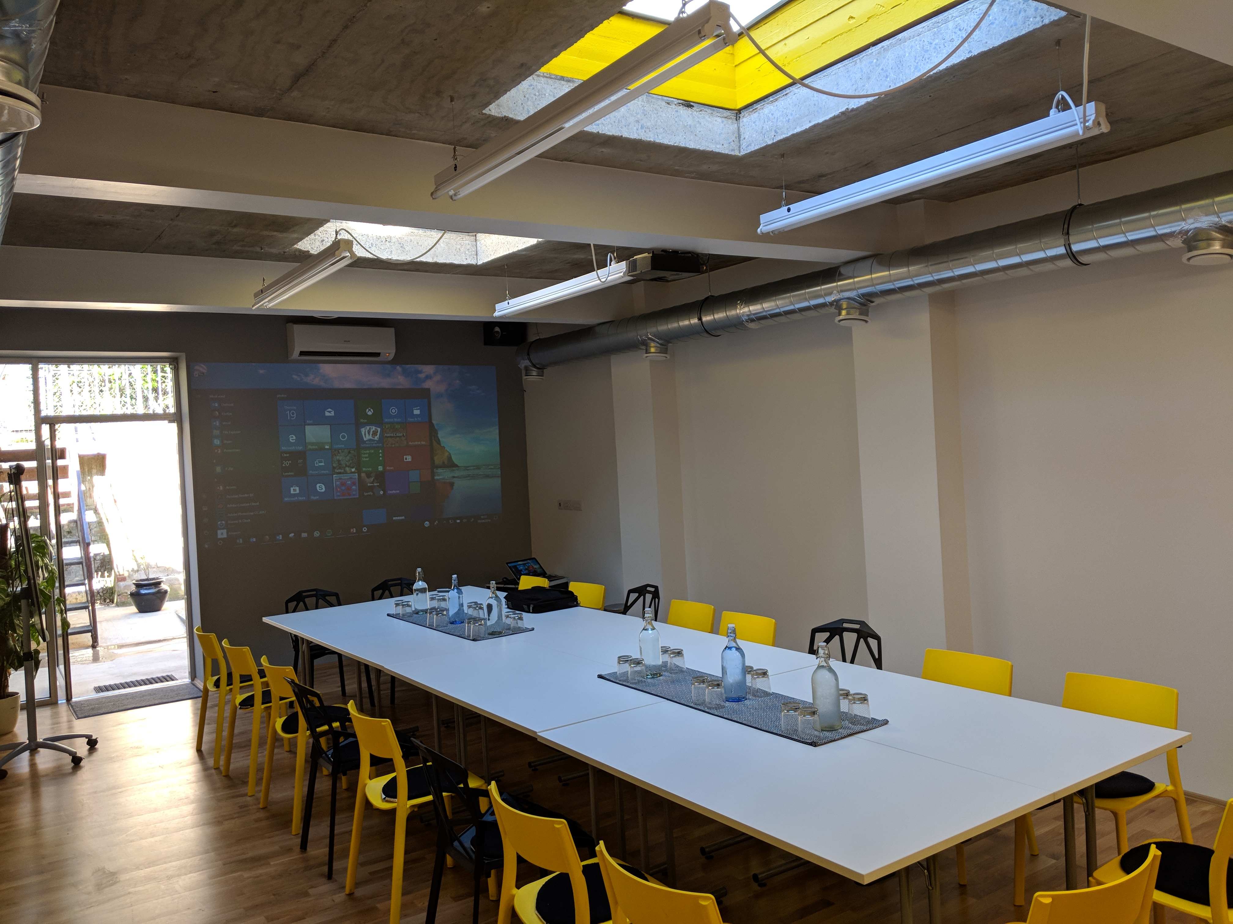 Modern conference room with large white table and yellow chairs, perfect for workshops.