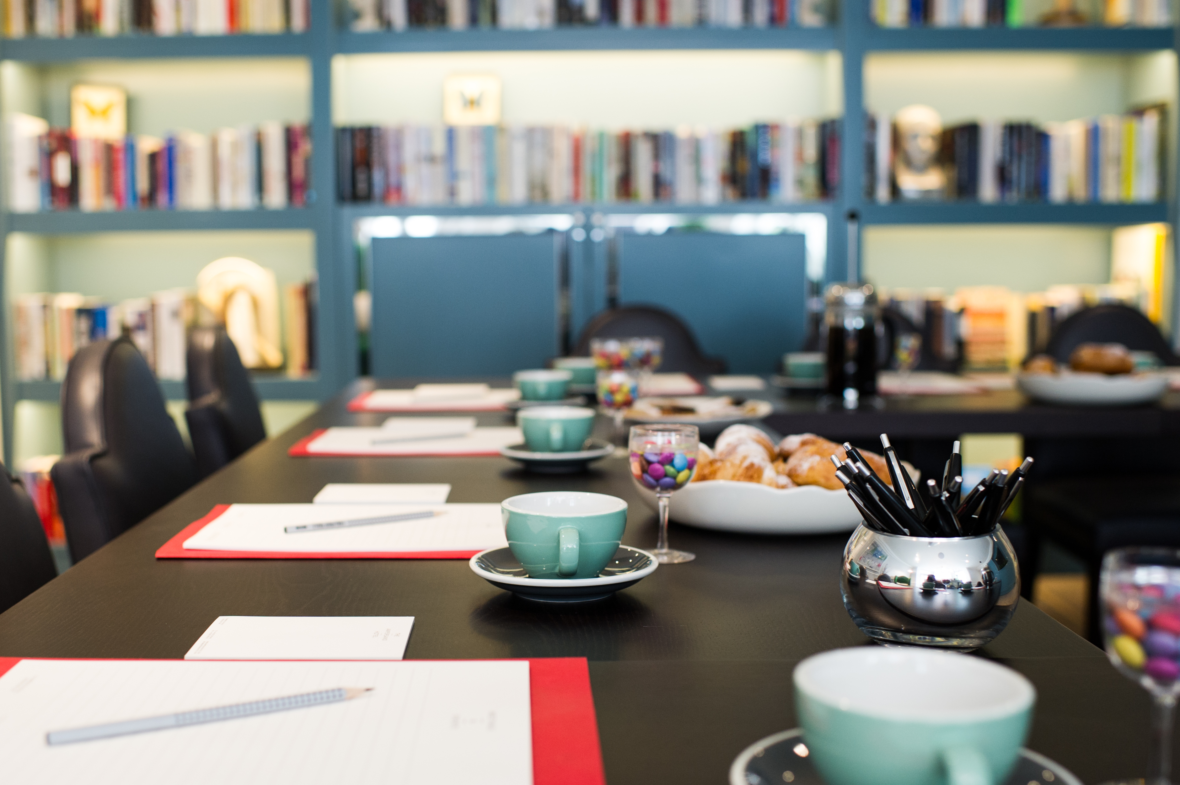 Meeting space in The Ampersand Hotel with long table, bookshelves, and refreshments.