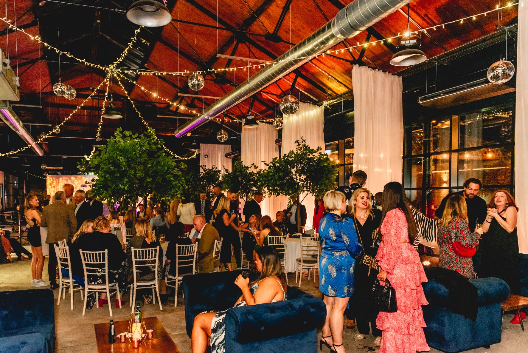 Vibrant wedding venue with elegant greenery and festive disco balls for events.