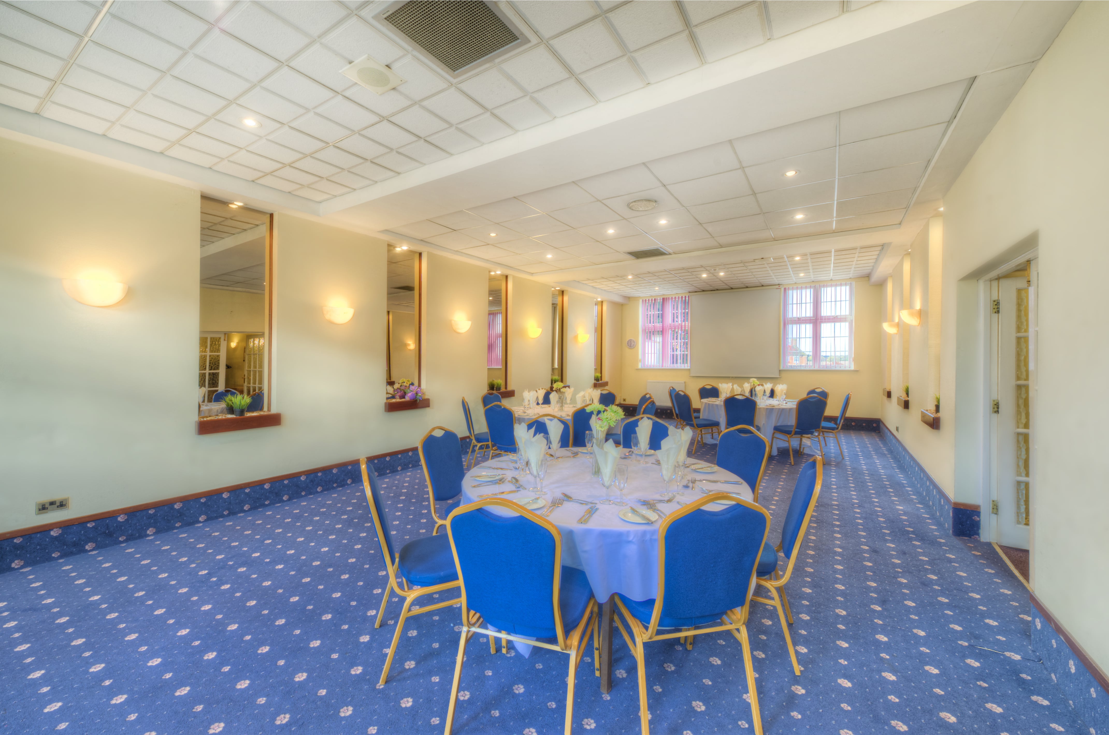 Meriden Suite at Quality Hotel Coventry, spacious event space with round tables and blue chairs.