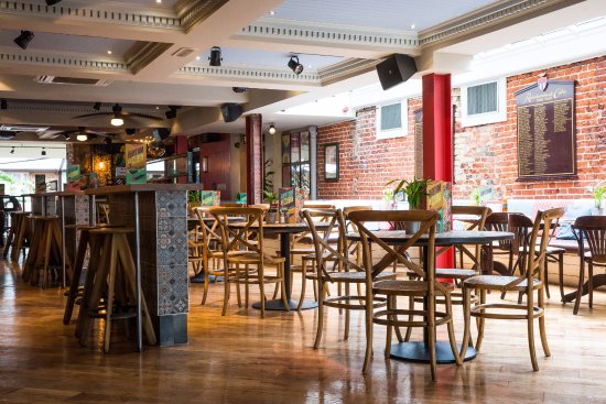 Versatile event space with wooden tables at Revolucion De Cuba Norwich for gatherings.
