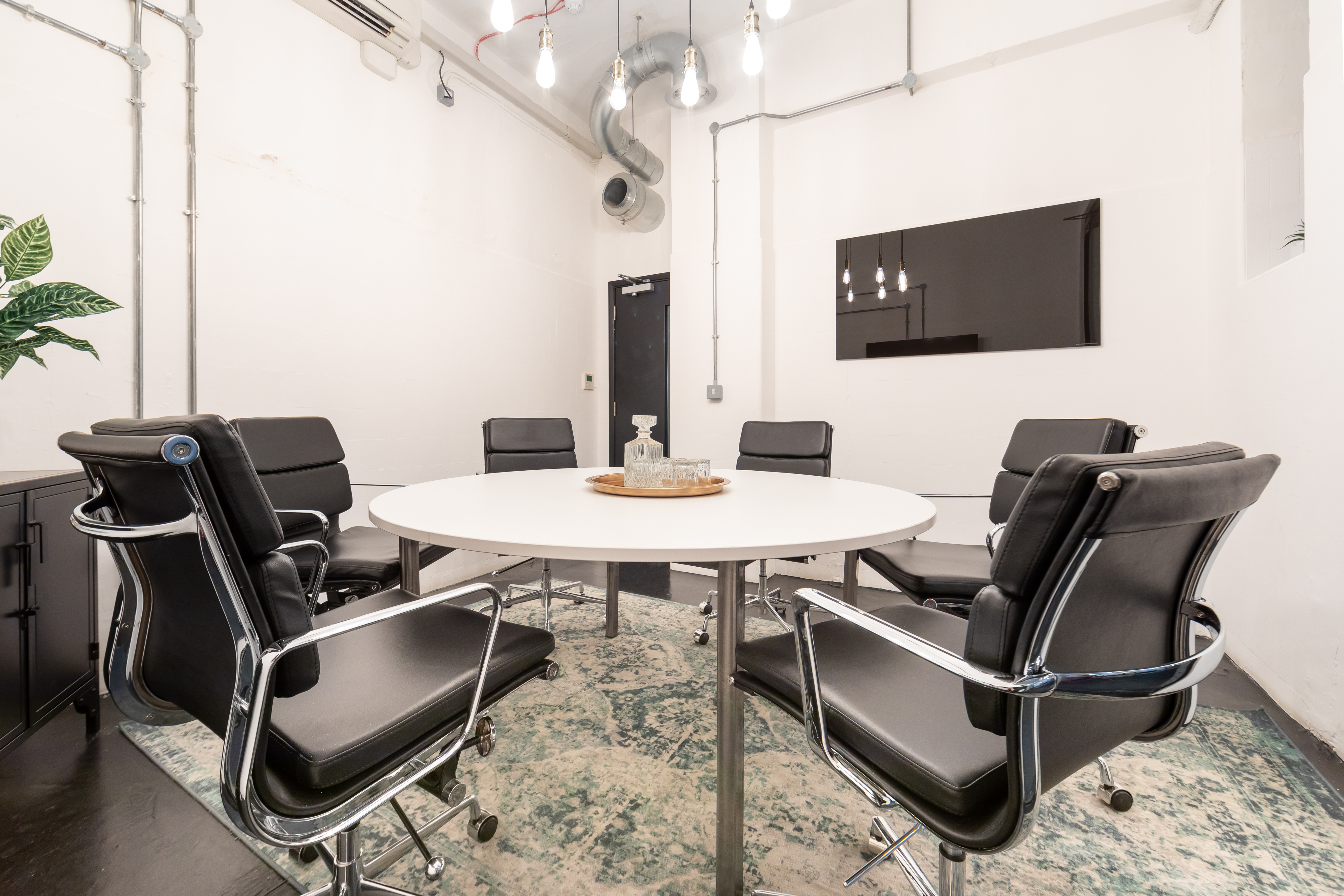 Modern conference room with round table and black chairs for meetings in Holborn.