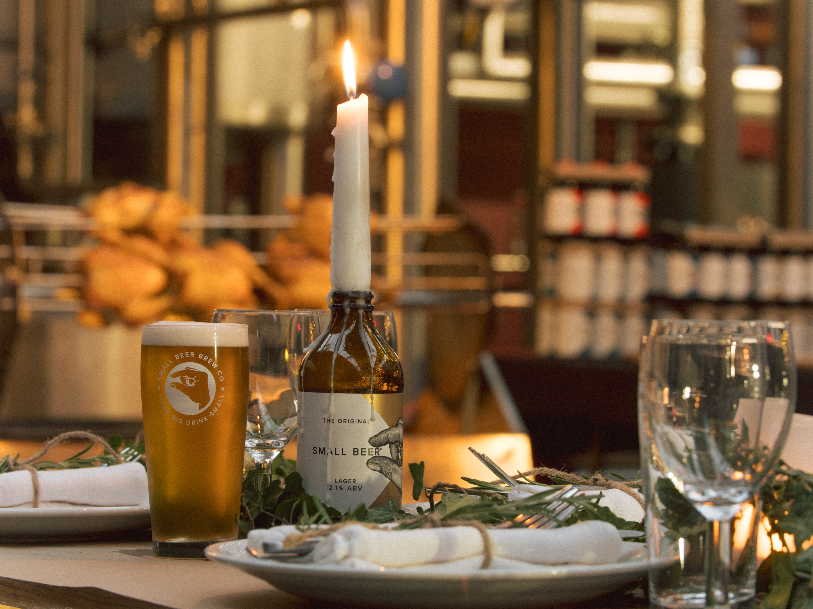 Elegant table setting with glassware and candles at Small Beer Brewery event.