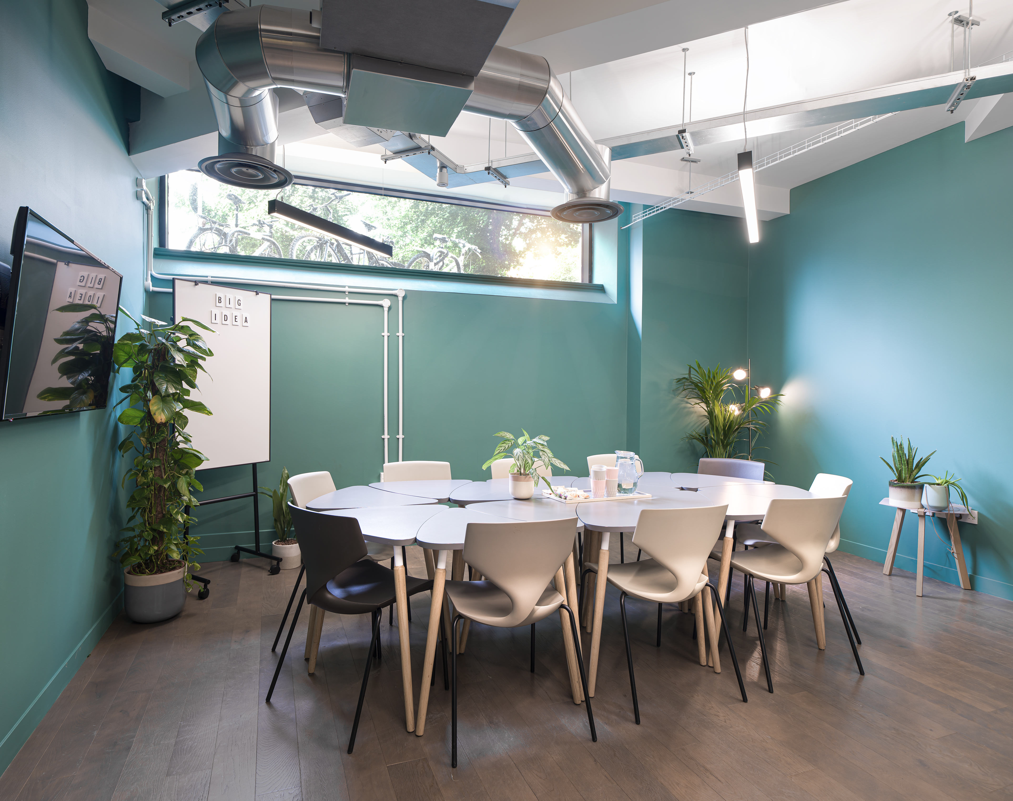Modern meeting room with round table and greenery for collaborative workshops.