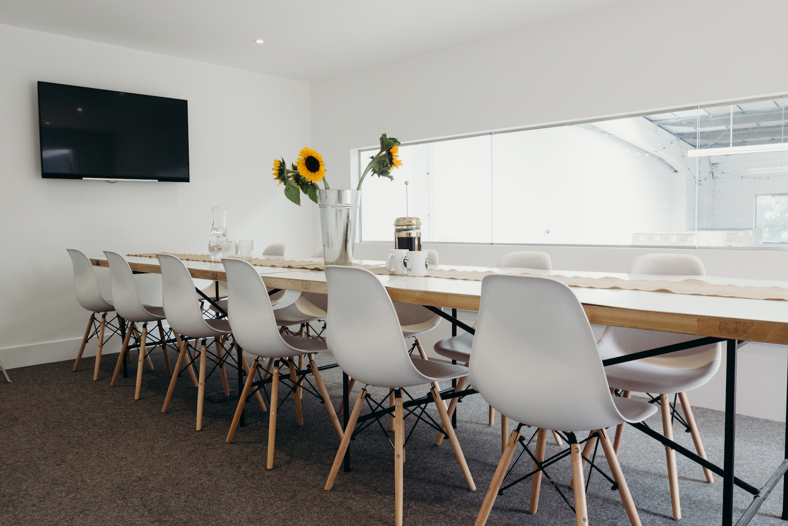 Modern boardroom with wooden table, white chairs, ideal for meetings and brainstorming.