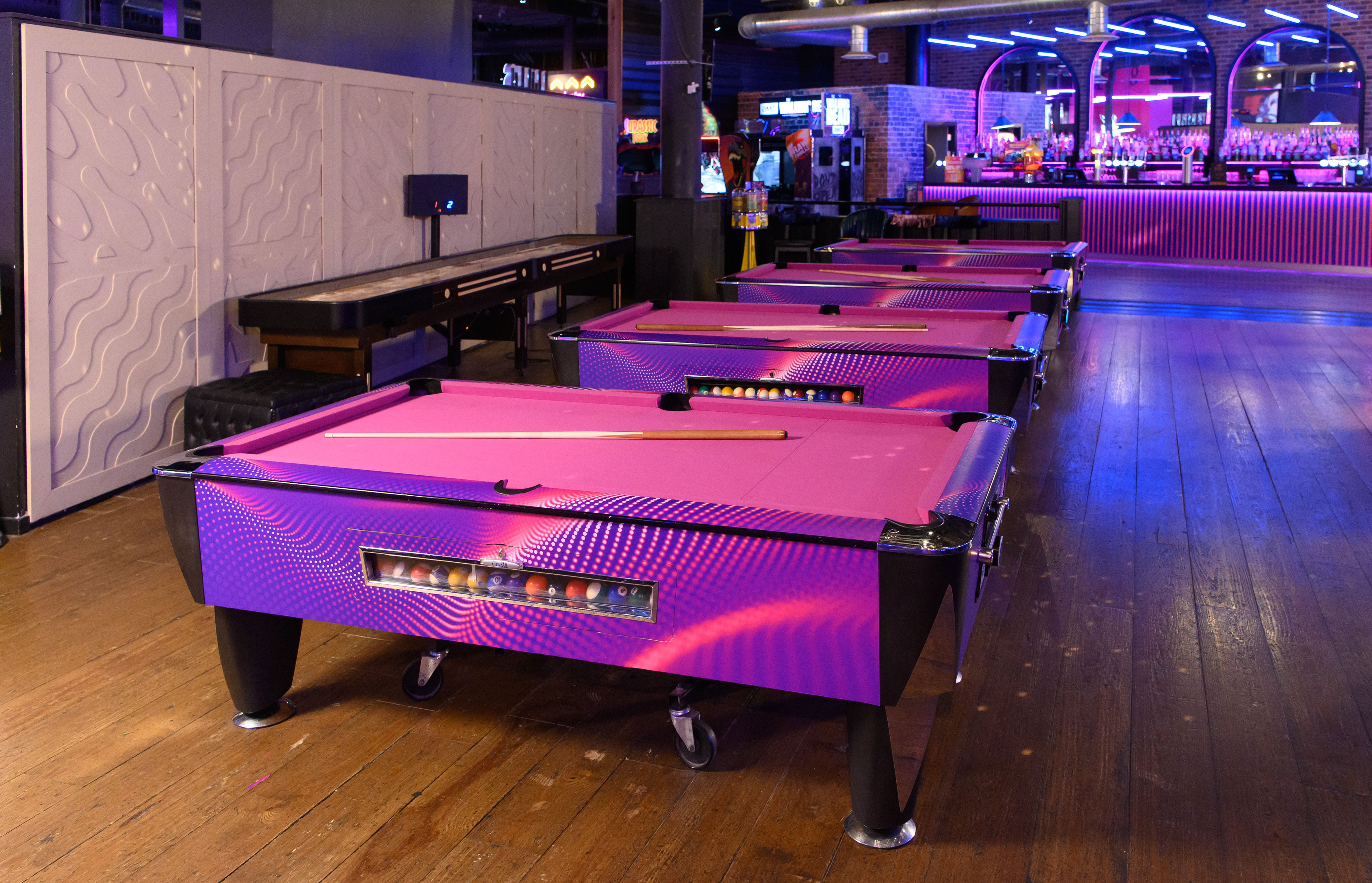 Vibrant Hollywood Bowl event space with pink pool tables for networking and gatherings.