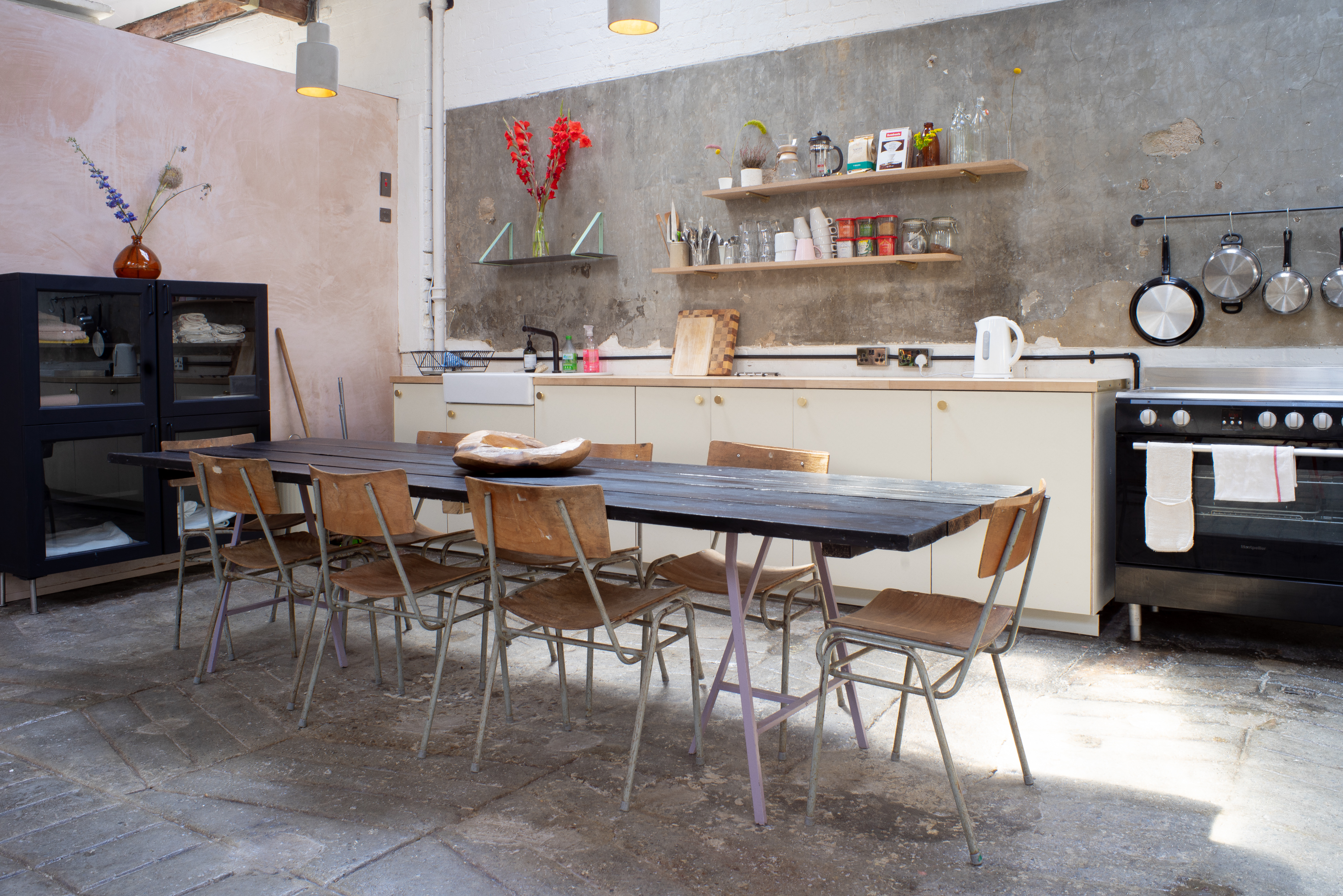 Modern kitchen space with long table for culinary events and gatherings.