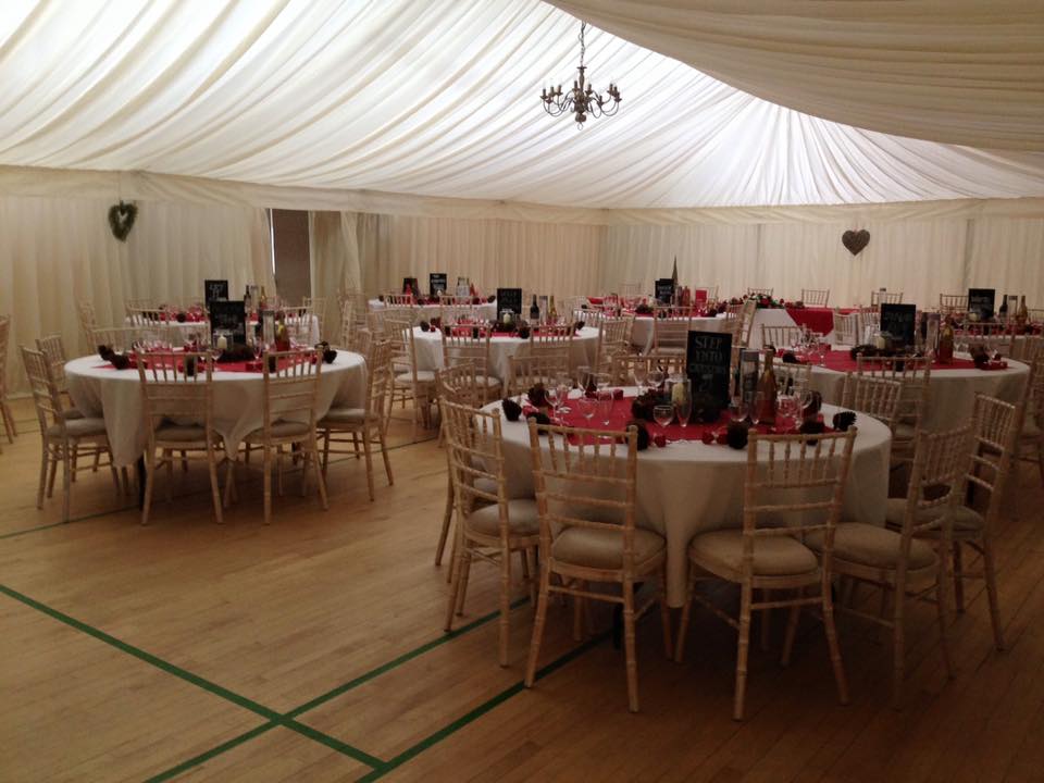 Elegant event space at Gamlingay Eco Hub with round tables and red decor.