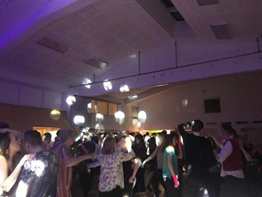 Vibrant event at Gamlingay Eco Hub with attendees dancing under dynamic lighting.