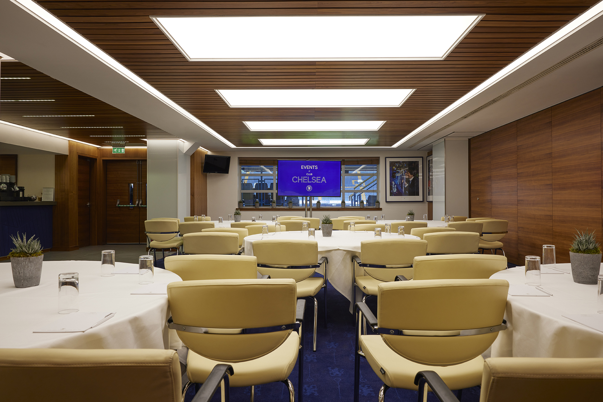 Vialli Suite at Chelsea FC: modern meeting space with round tables and yellow chairs.