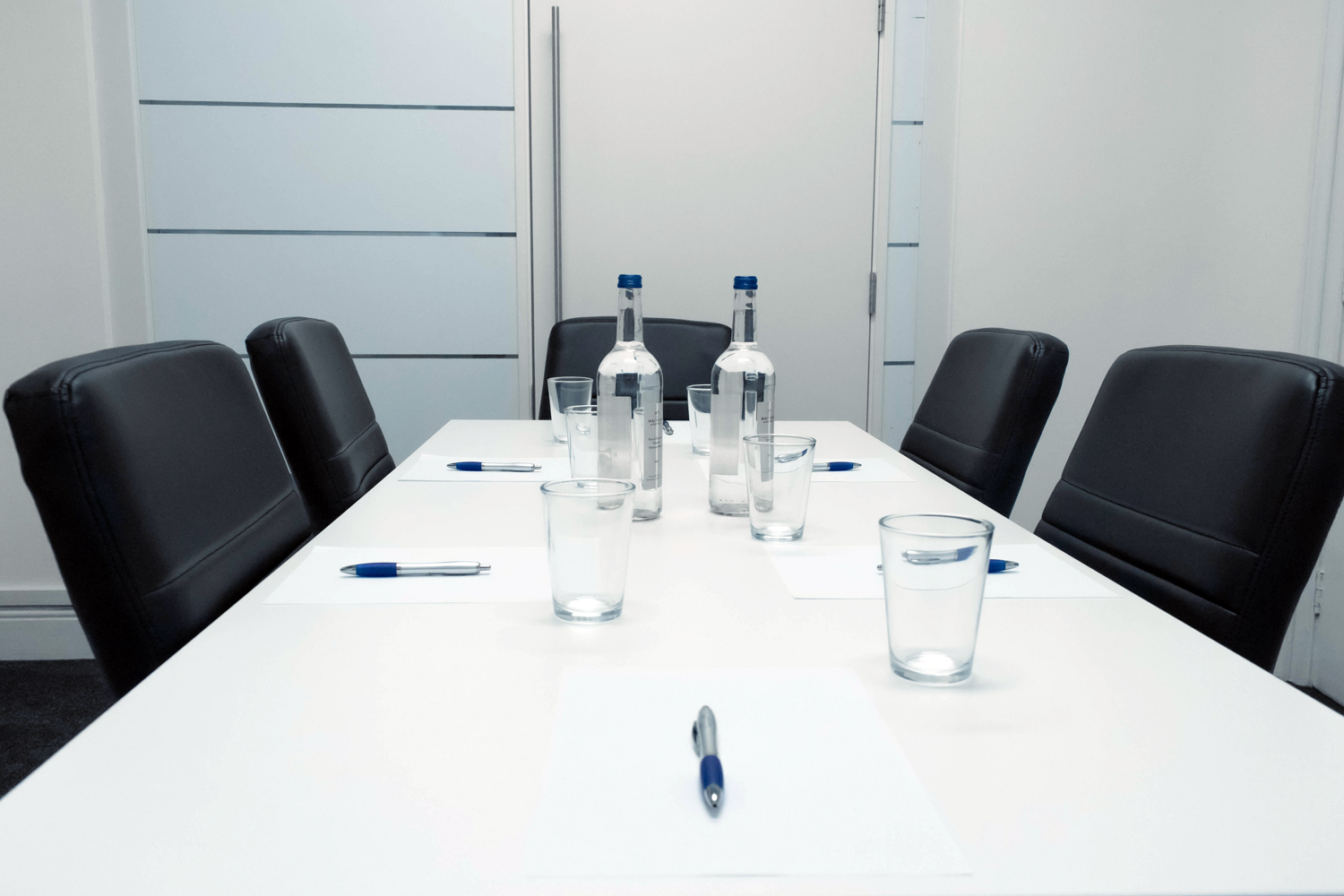 Modern meeting room in Oxford Circus, set for collaboration with notepads and water bottles.