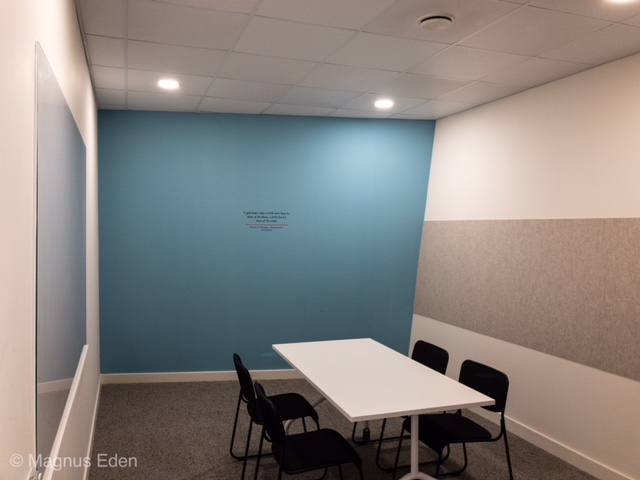 Modern meeting room with light blue wall, ideal for workshops and brainstorming sessions.