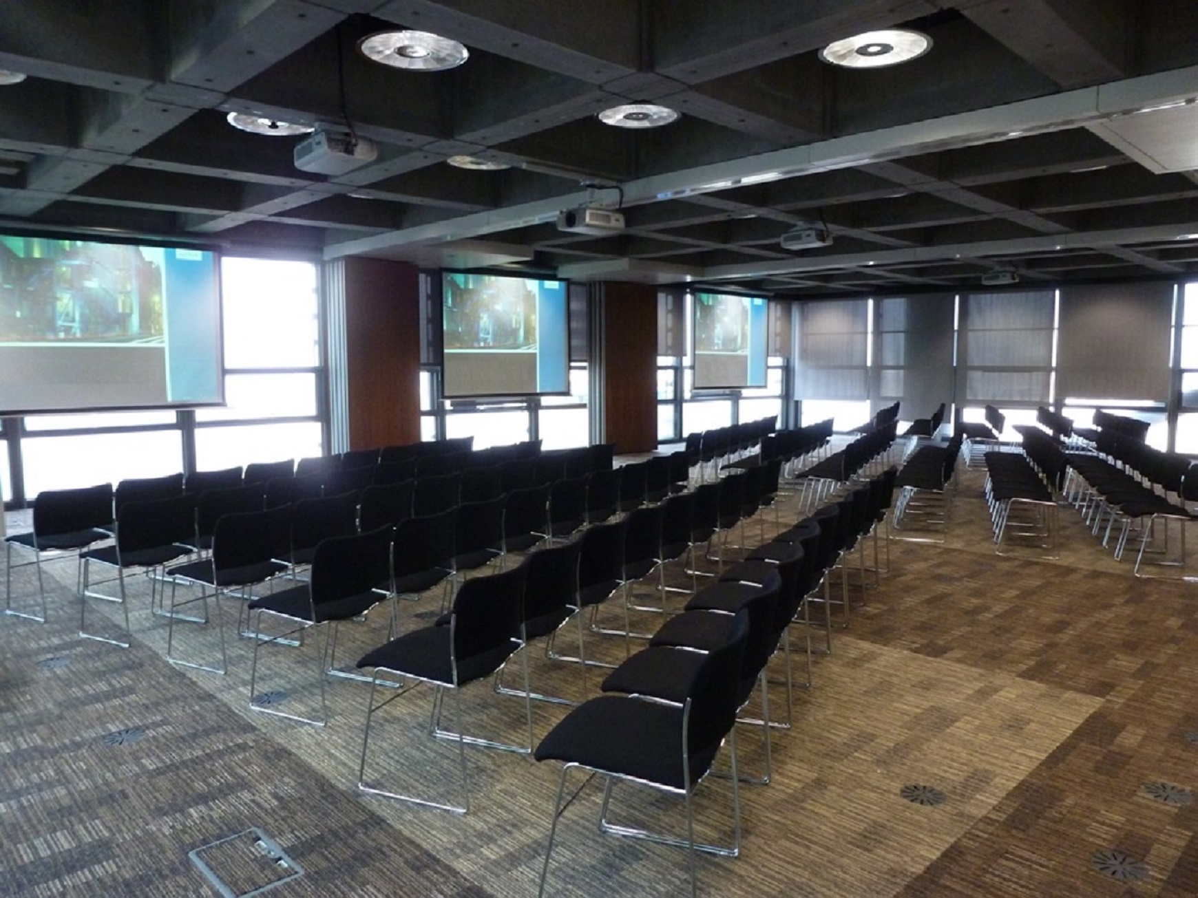 Modern London event space with black chairs for presentations and dual screens.
