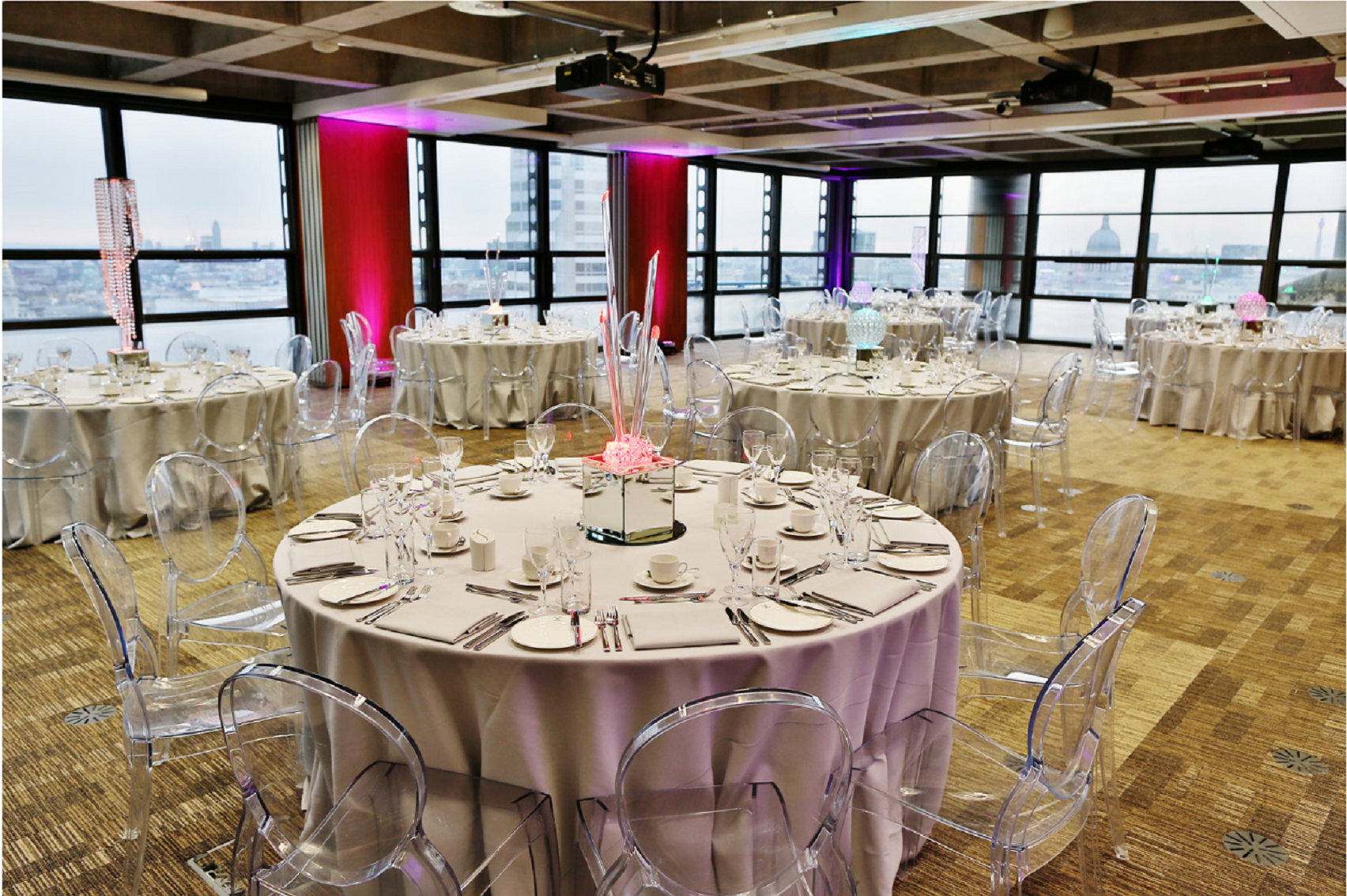Elegant London Rooms event space with round tables and modern acrylic chairs. Perfect for weddings.