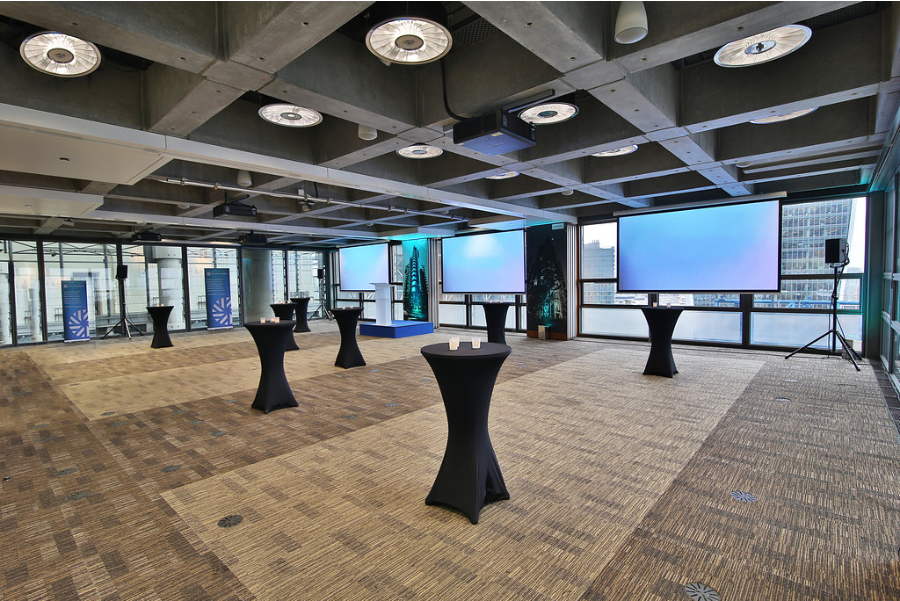 Modern event space in The London Rooms, featuring sleek black cocktail tables and city views.