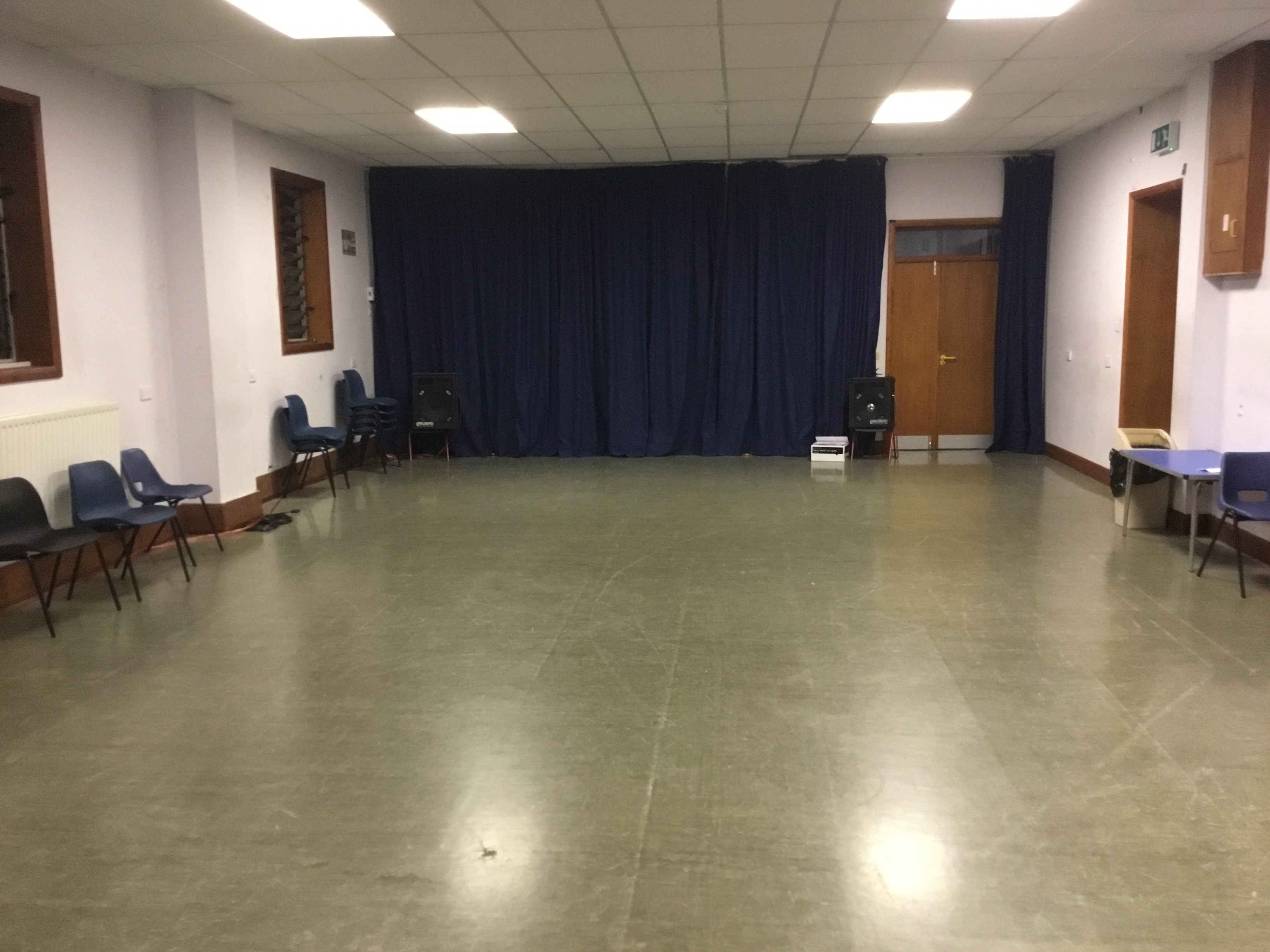 Spacious meeting room with blue curtains, ideal for workshops and presentations.