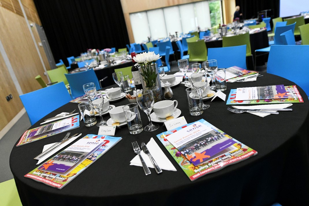 Elegant event space at The Buzz, featuring black tablecloths and colorful chairs.