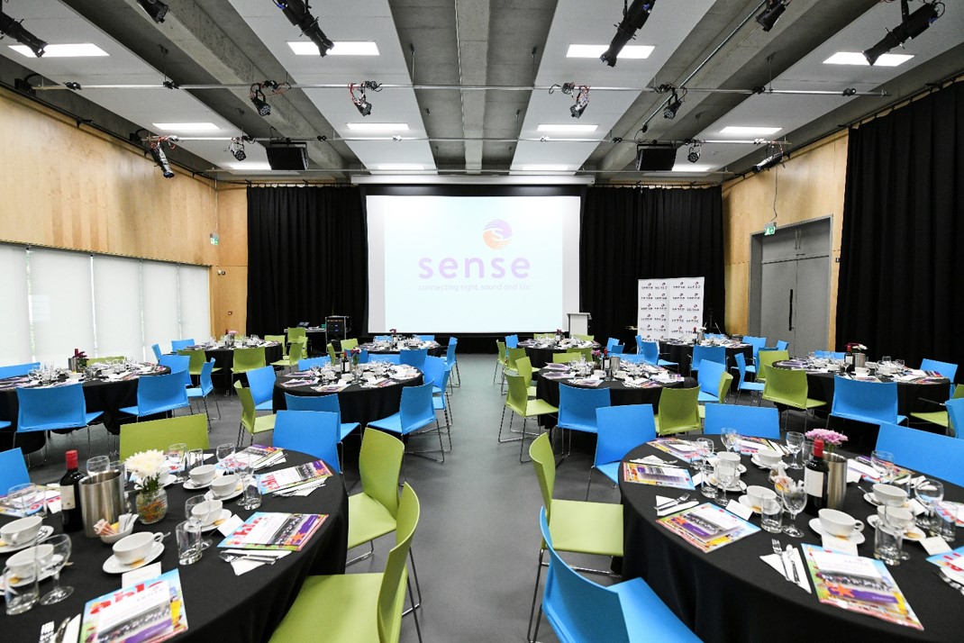 Formal event space at The Buzz, featuring round tables and vibrant blue chairs.