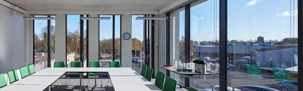 Modern meeting room with large windows, green chairs for productive brainstorming sessions.