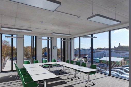 Modern meeting room with flexible table and ergonomic green chairs for workshops.