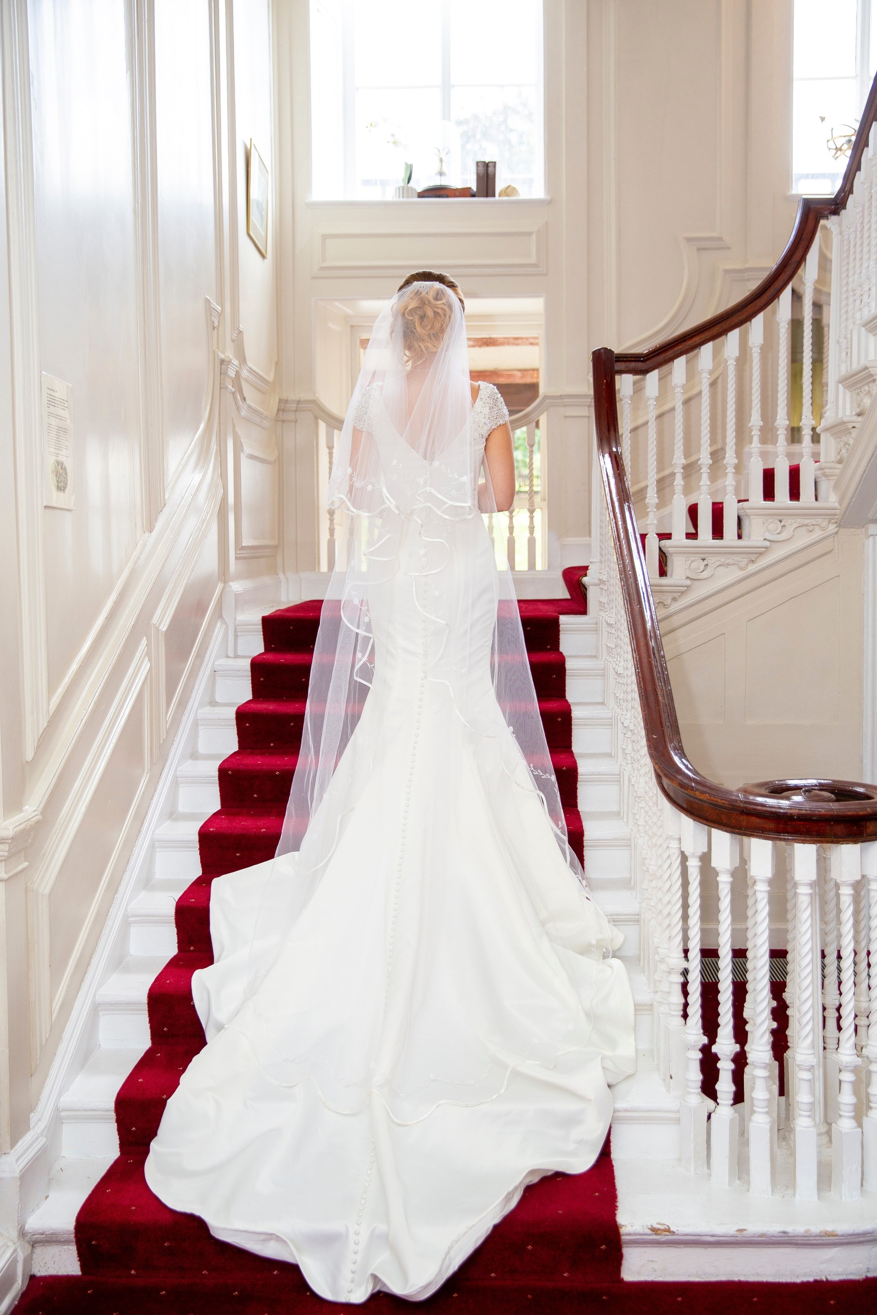 Bride ascending grand staircase at The Commissioner's House, perfect for weddings.