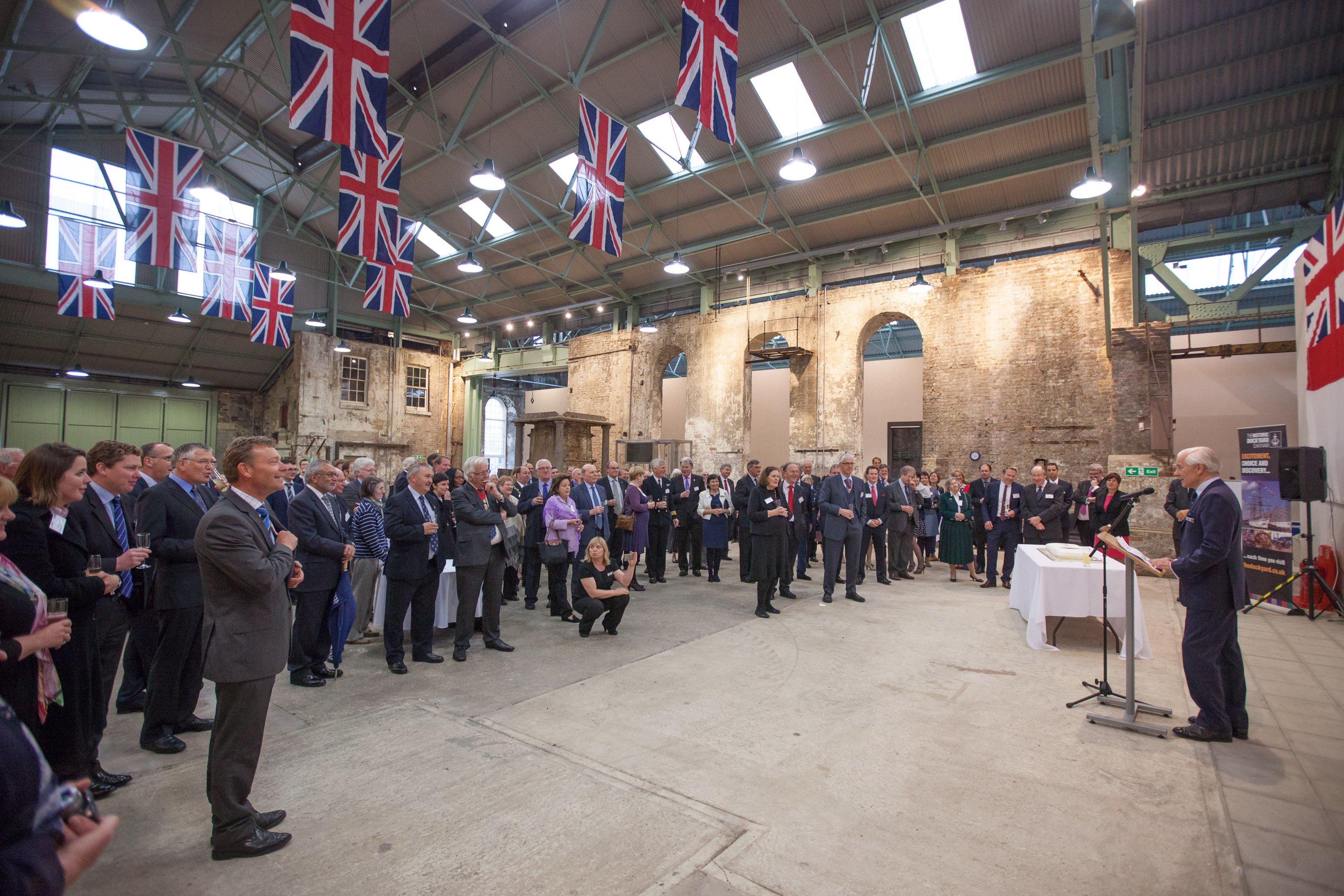 The Commissioner's House & Gardens event with speaker, exposed brick walls, corporate gathering.