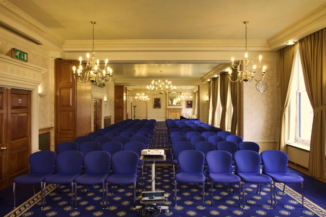 Meeting room with blue chairs, elegant decor for presentations and workshops.
