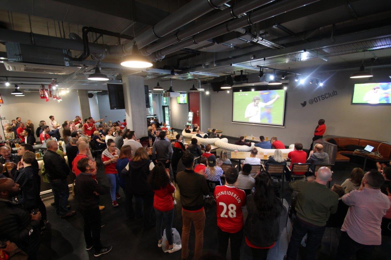 Old Trafford Supporters Club event space with fans enjoying a live sports match viewing.