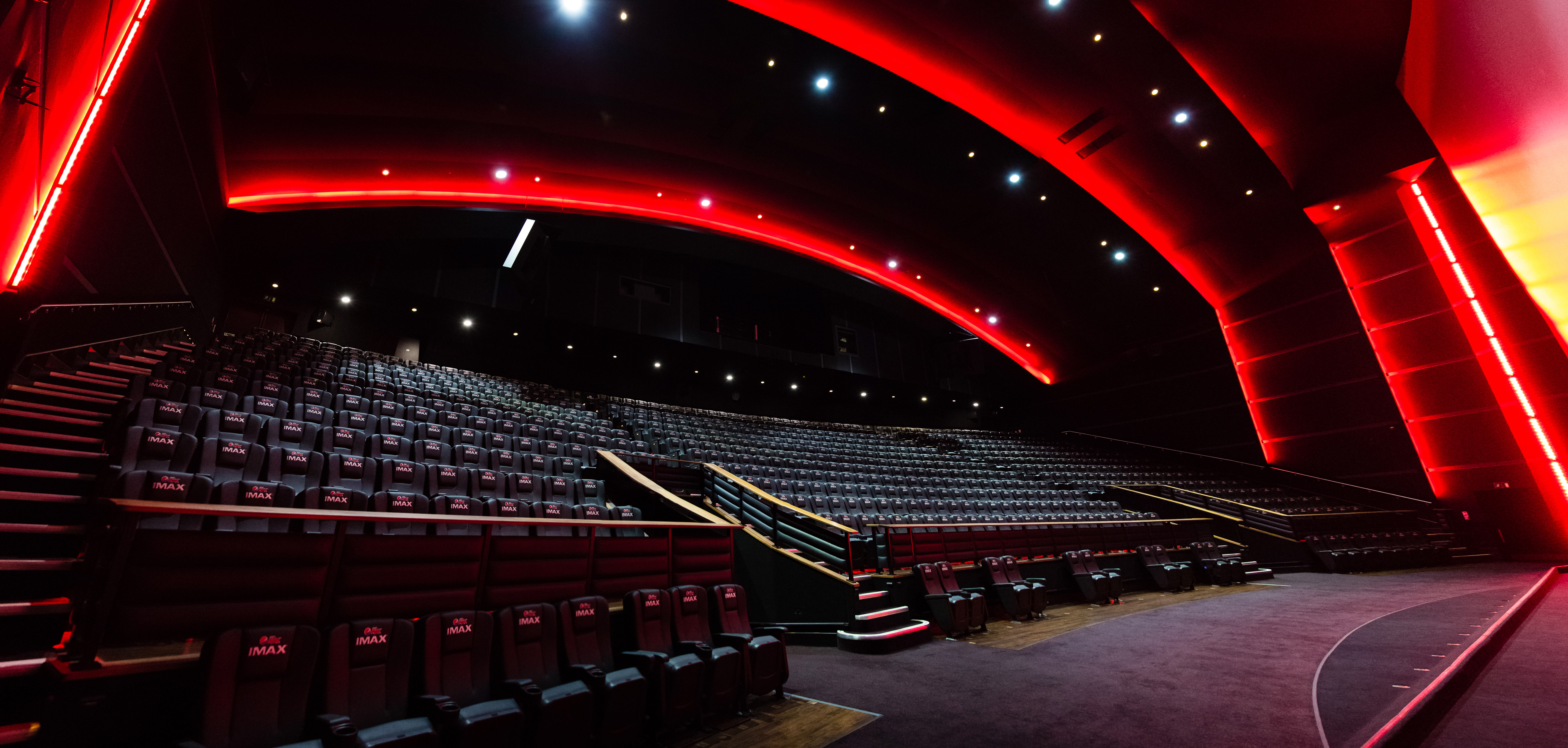 Modern IMAX auditorium at Cineworld Leicester Square with tiered seating and red lighting.