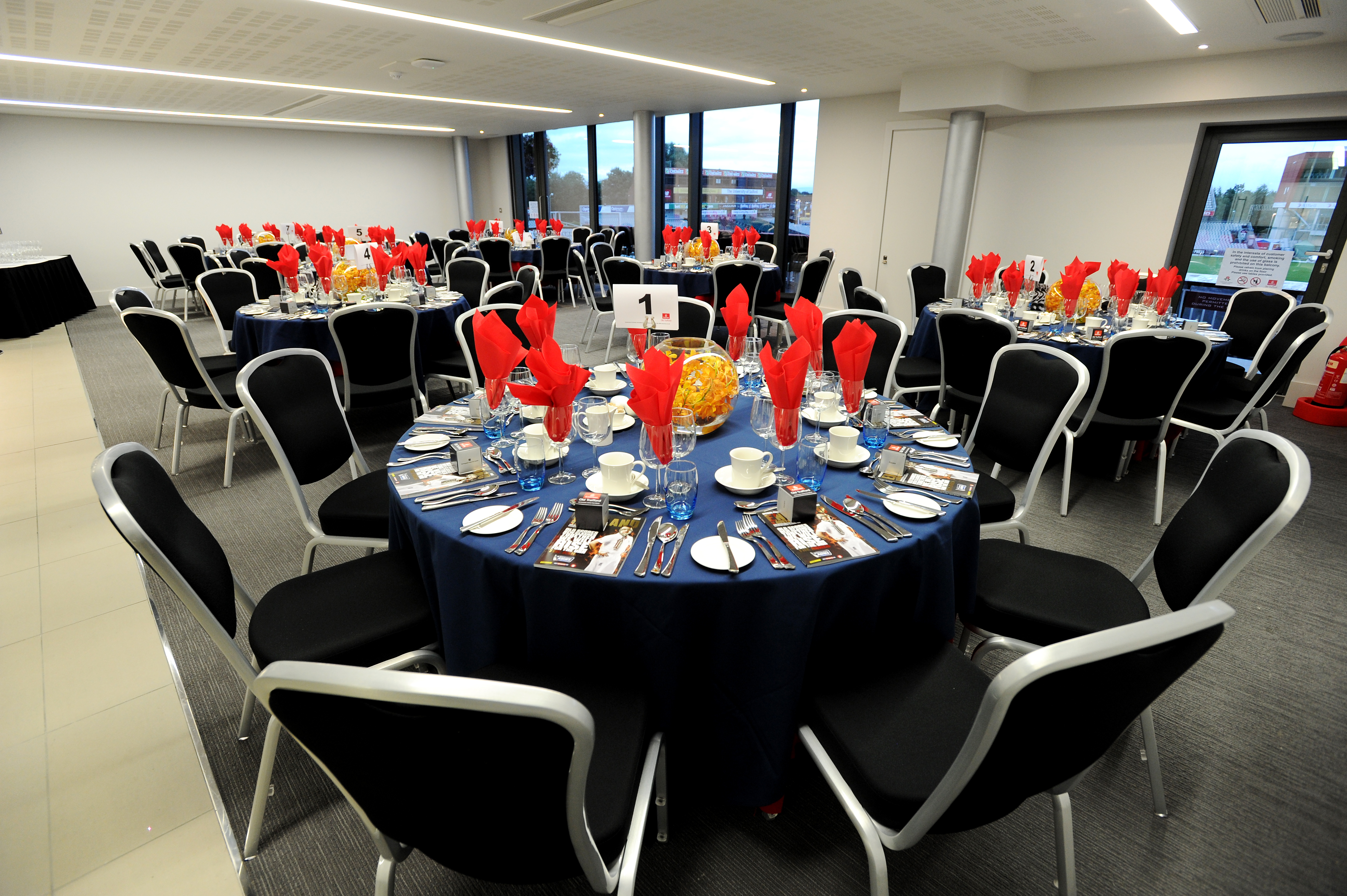 Elegant banquet setup in The Club Suite, Emirates Old Trafford, with navy blue tables.