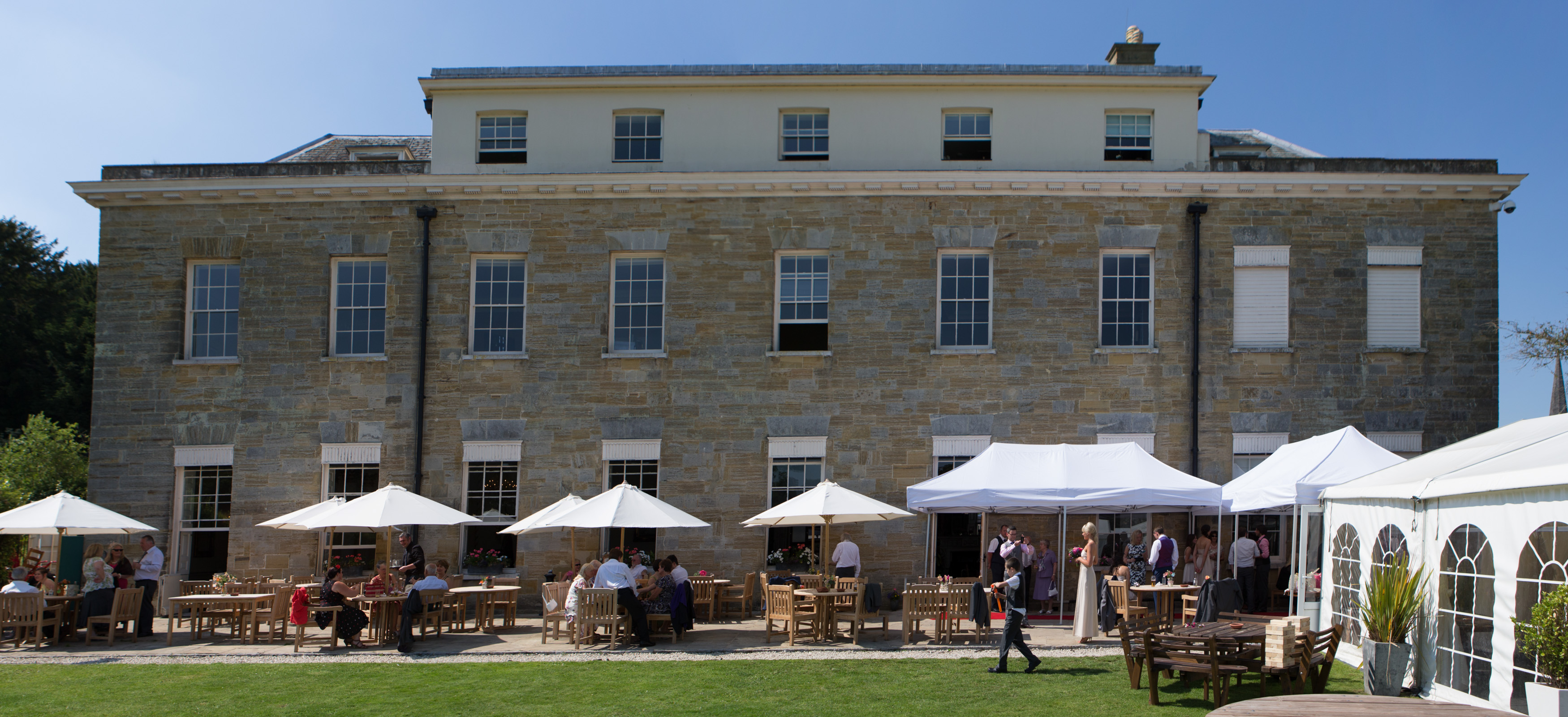 Outdoor event space at Proud Country House with charming stone building and lush lawn.
