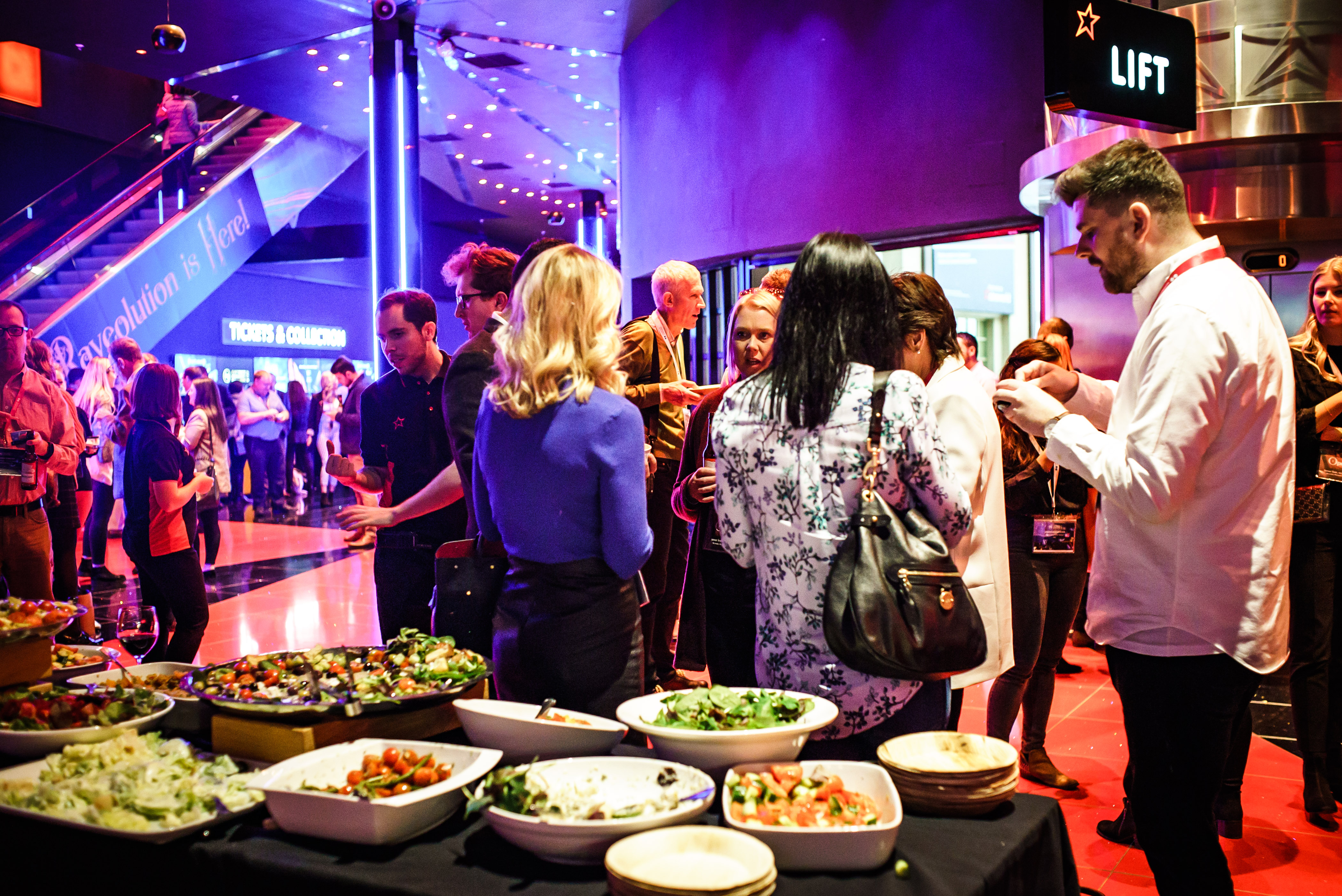 Vibrant networking event at Cineworld O2 Greenwich with colorful lighting and food spread.