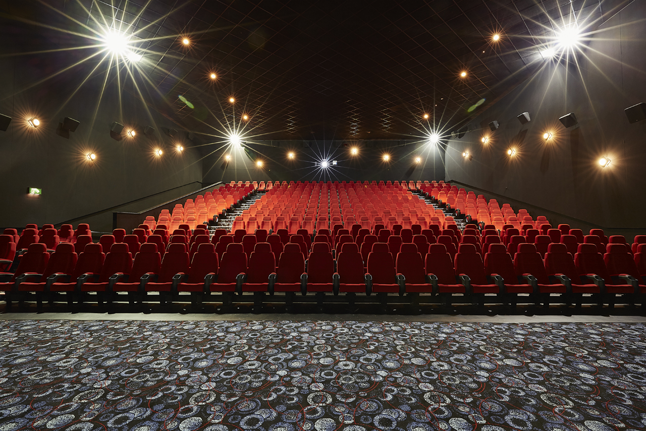 Large screen theater with red seating, ideal for corporate events and film screenings.