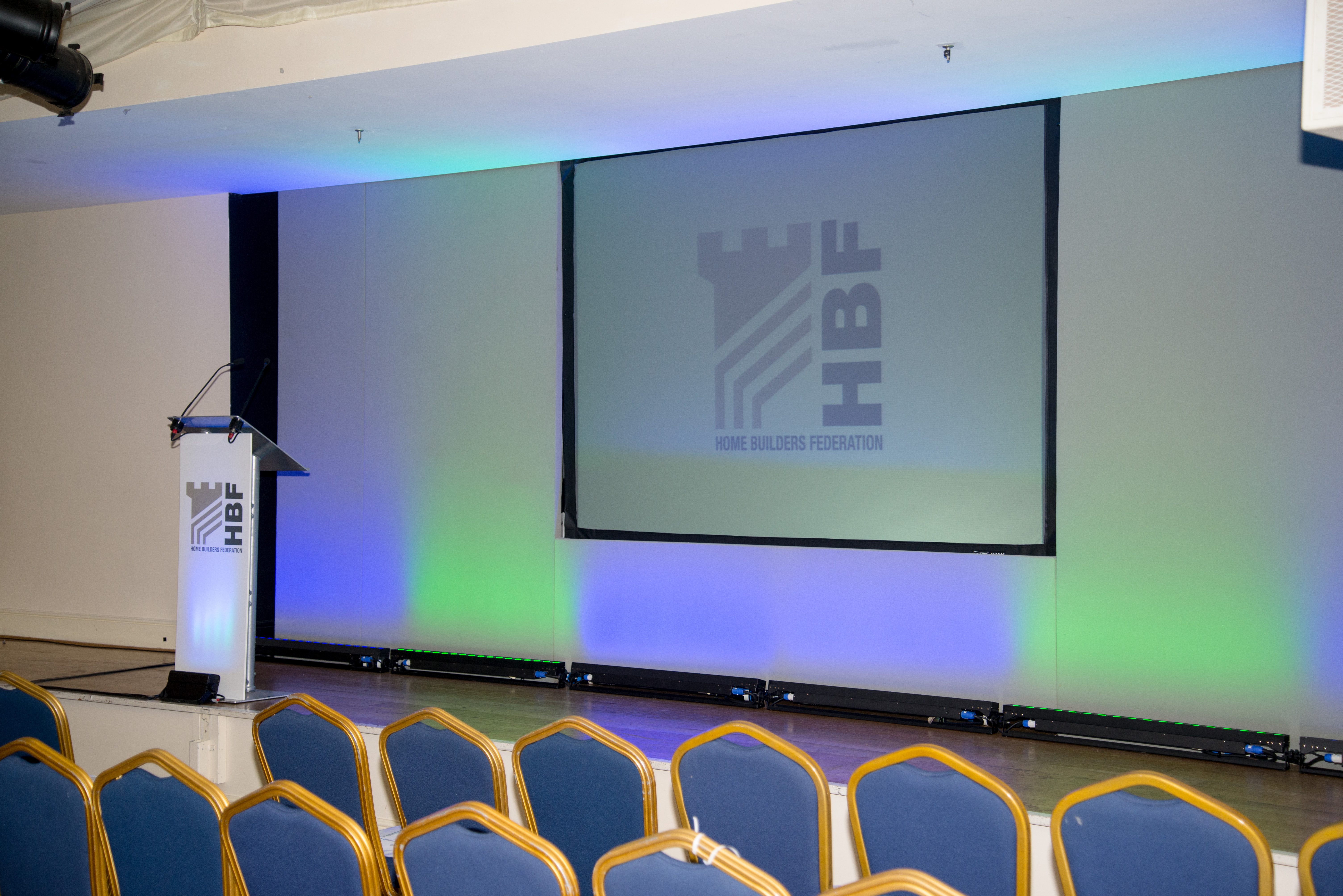 Event space at The Marquee, DW Stadium with podium and projection screen for presentations.