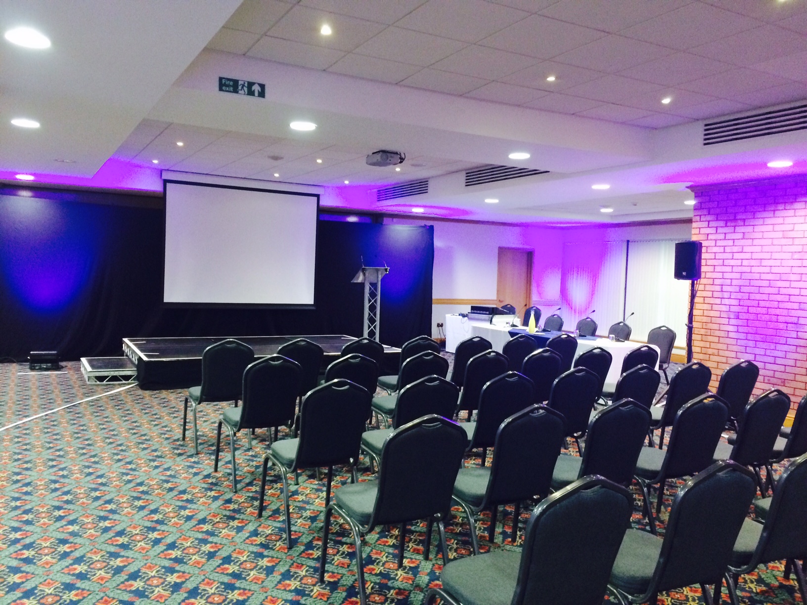 Springfield Lounge event space with stage and projector for conferences and presentations.