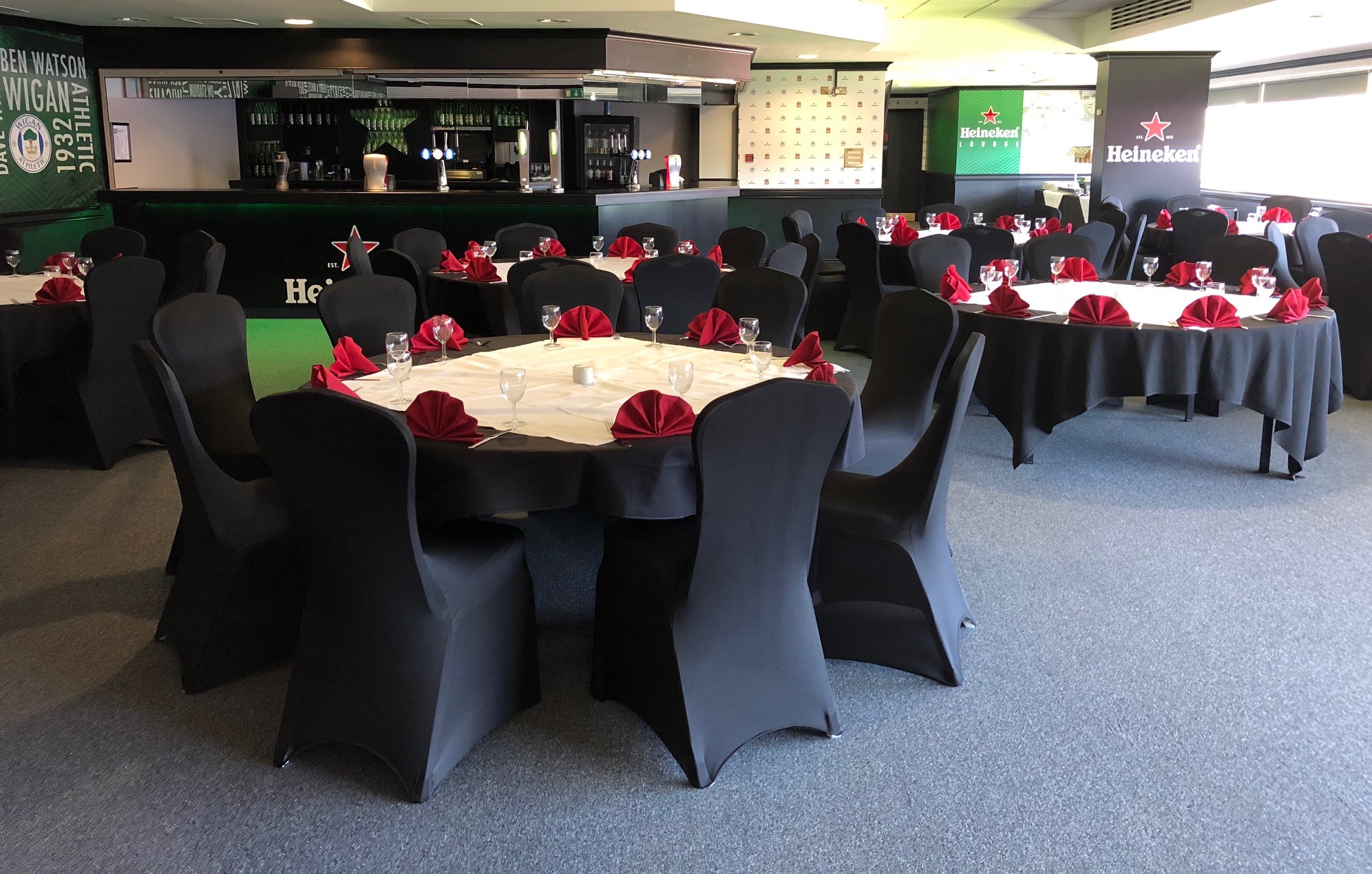 Elegant event space at The Carling Lounge, DW Stadium with round tables and red napkins.