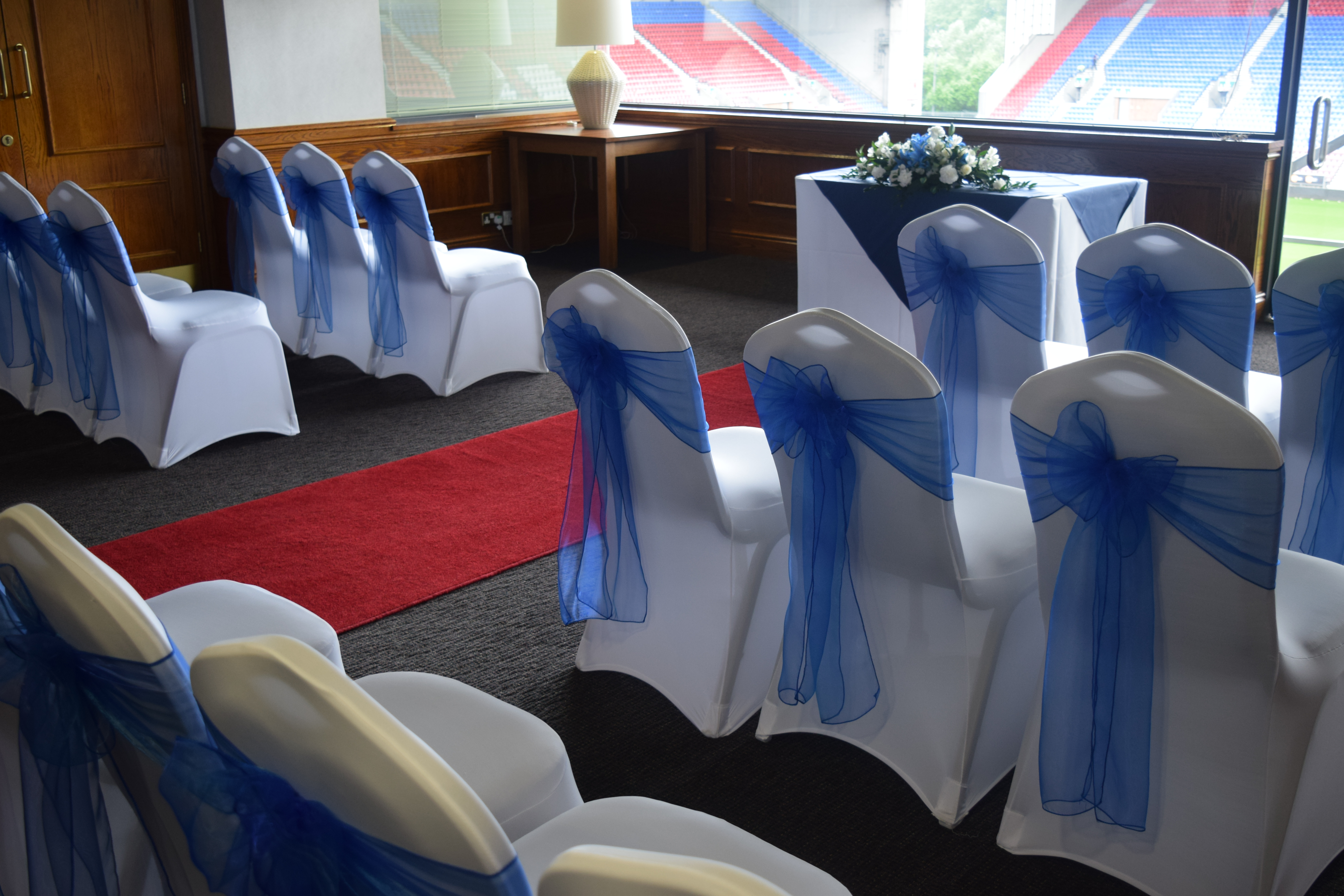 Elegant event space in DW Stadium with blue-sashed chairs and red carpet for ceremonies.