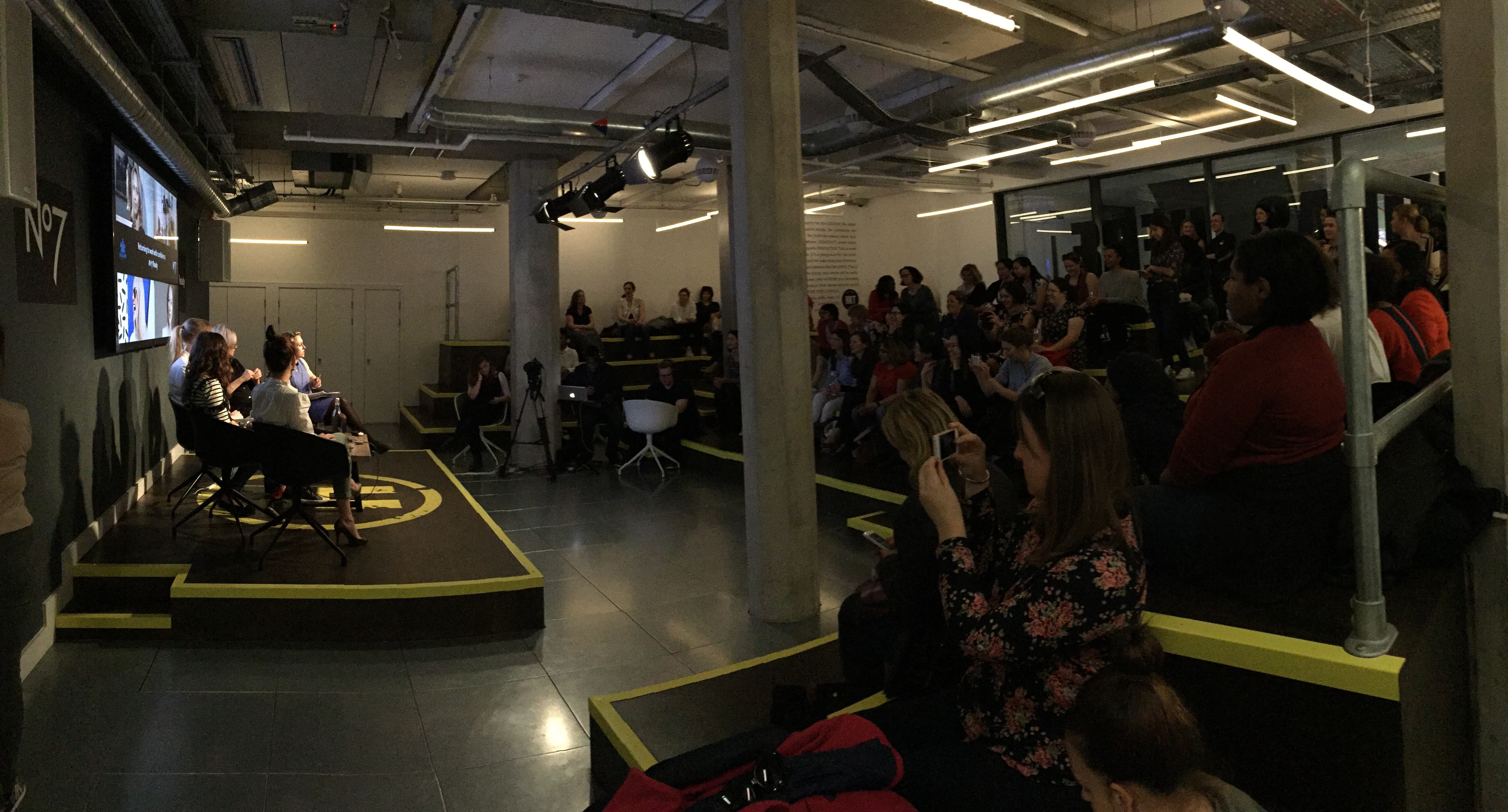 Panel discussion in modern event space with tiered seating for engagement and networking.