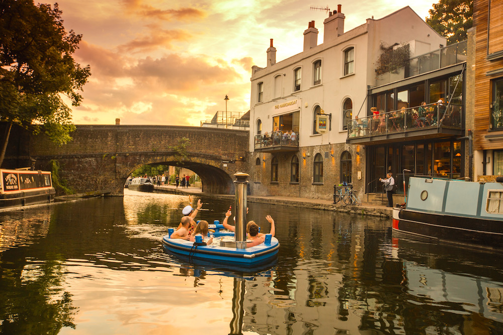 Floating hot tub at sunset in picturesque canal, ideal for outdoor events and networking.