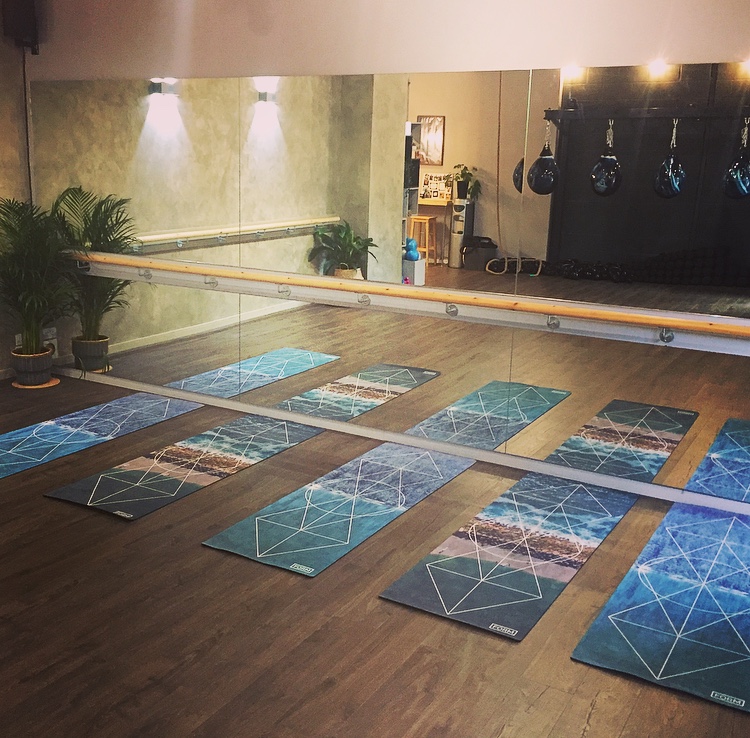 Yoga studio with polished wooden floor and mirrored wall, perfect for wellness events.