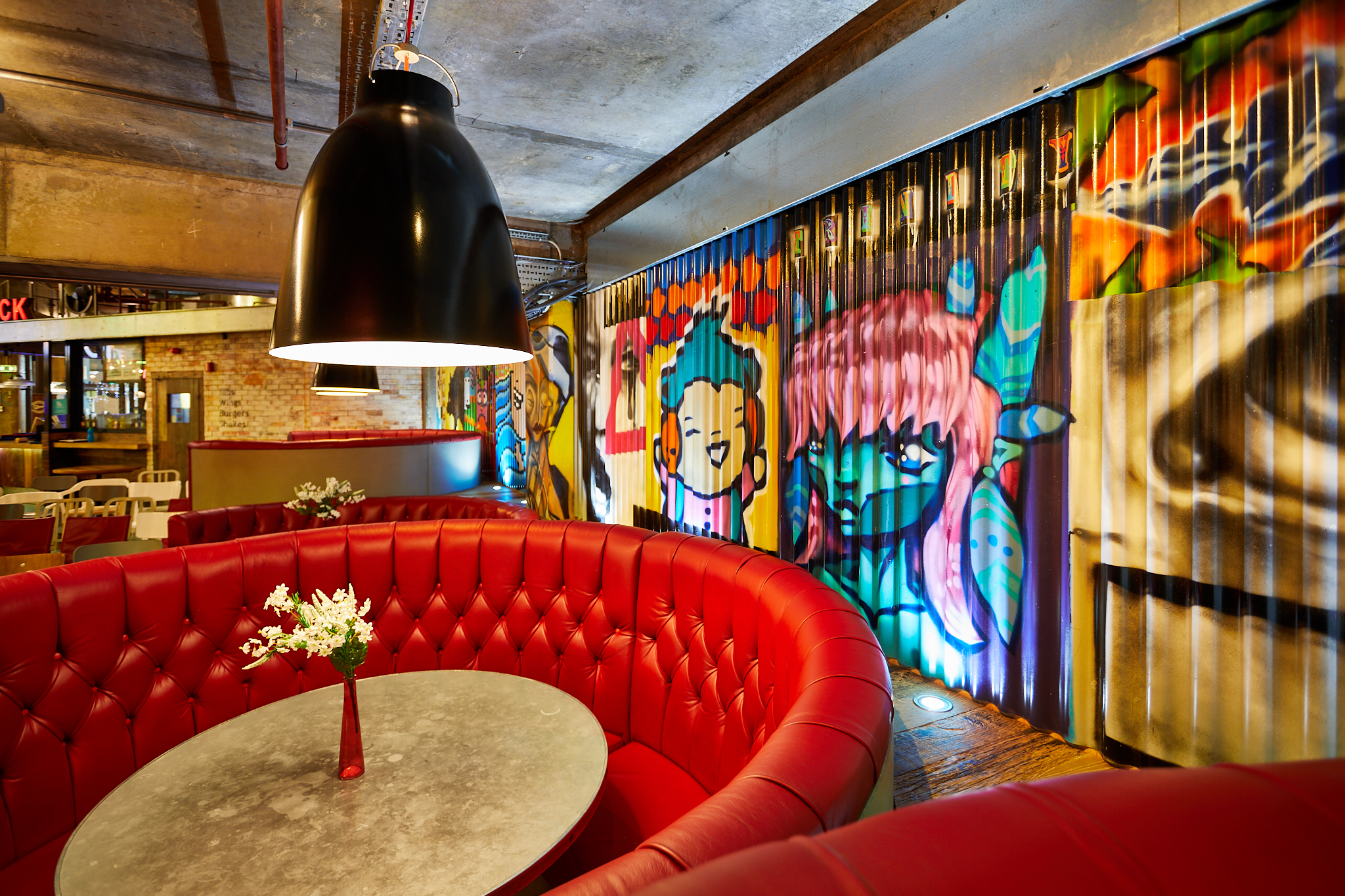 Vibrant urban courtyard with graffiti backdrop, perfect for casual meetings and events.