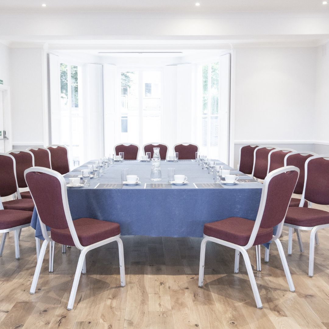 Ballroom at Linden House set for roundtable discussion with blue tablecloth and natural light.