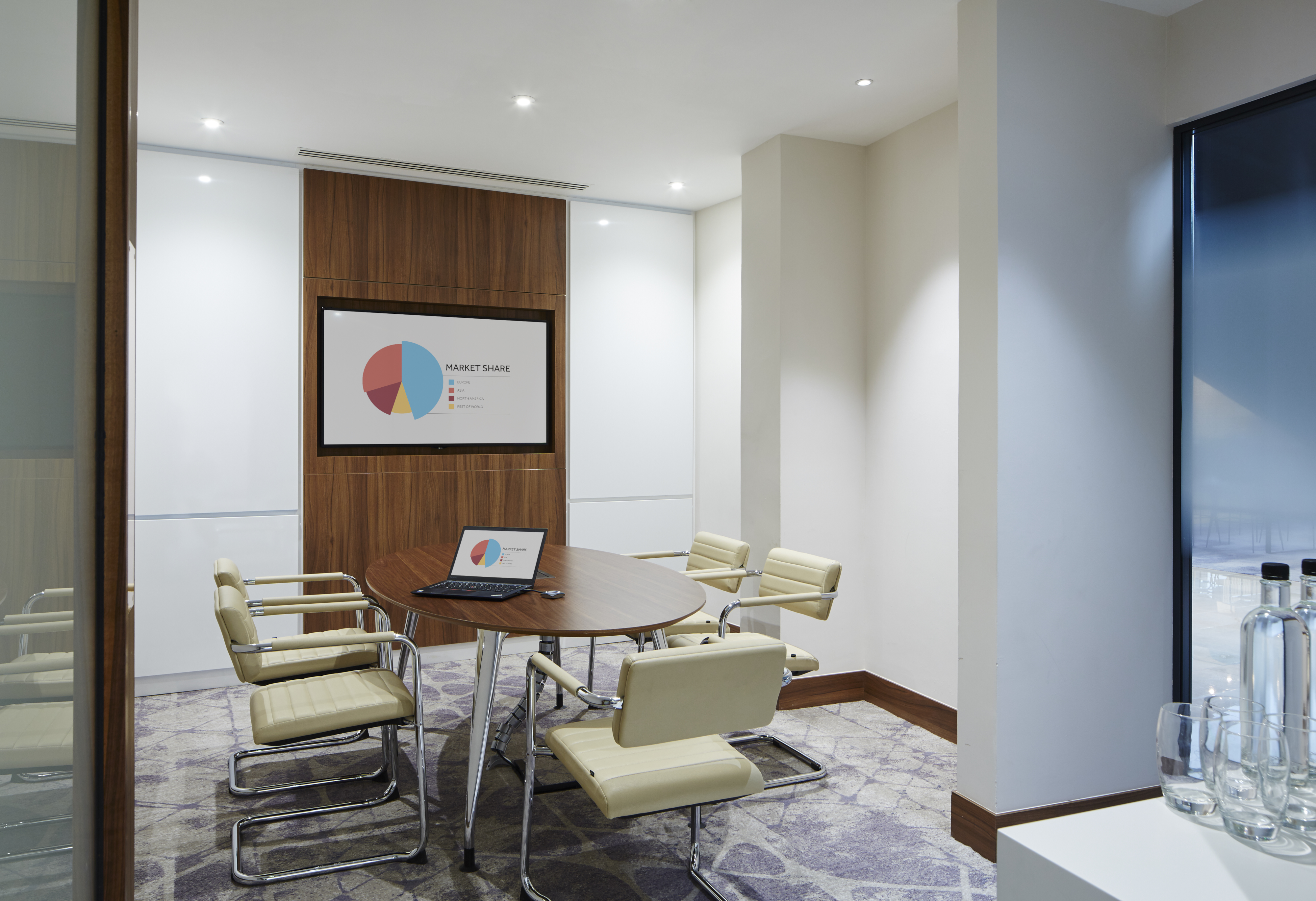 Modern meeting room with round table at London Heathrow Marriott for strategic planning.